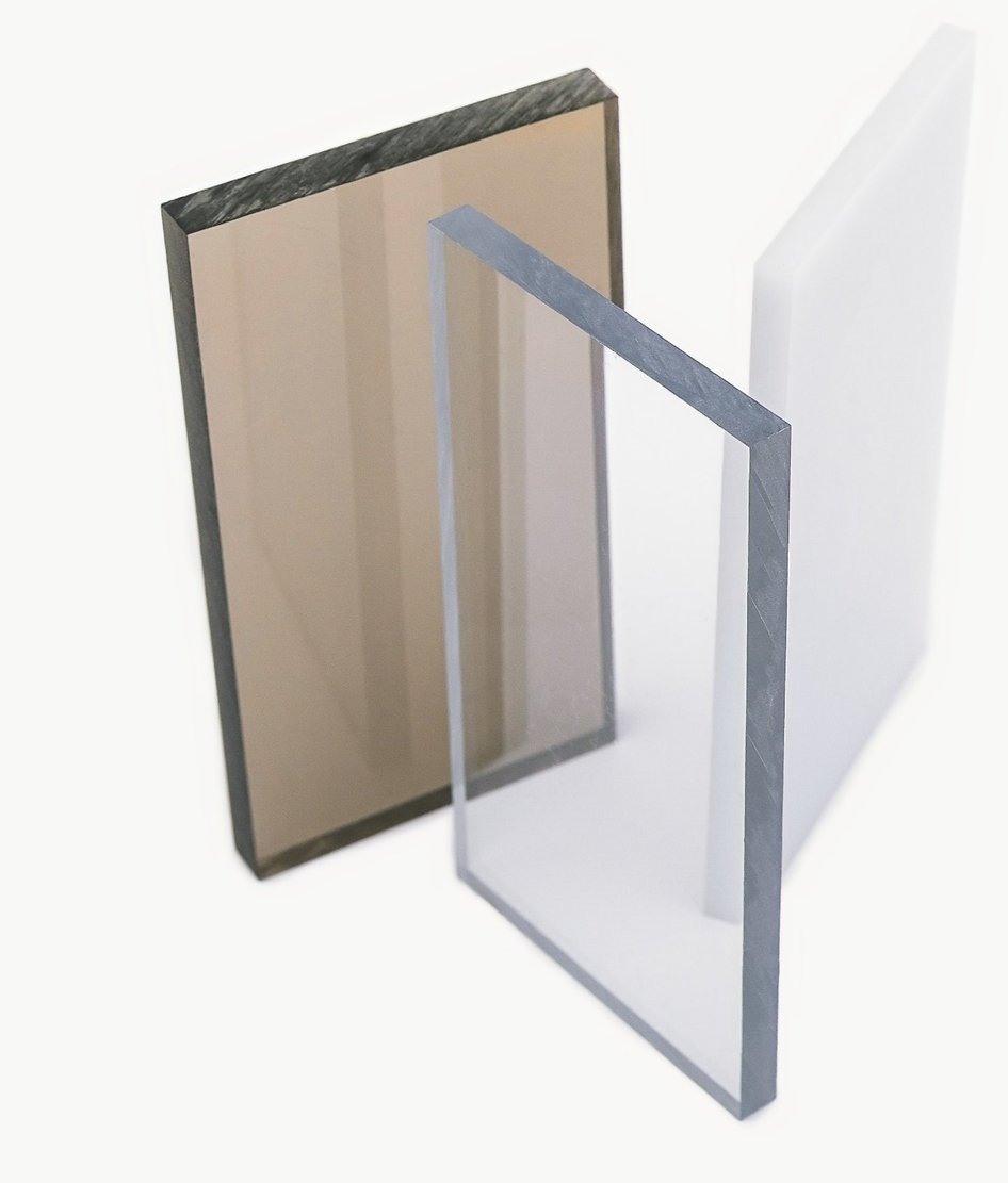 Three sheets of acrylic plastic in different tints: brown, clear, and white.