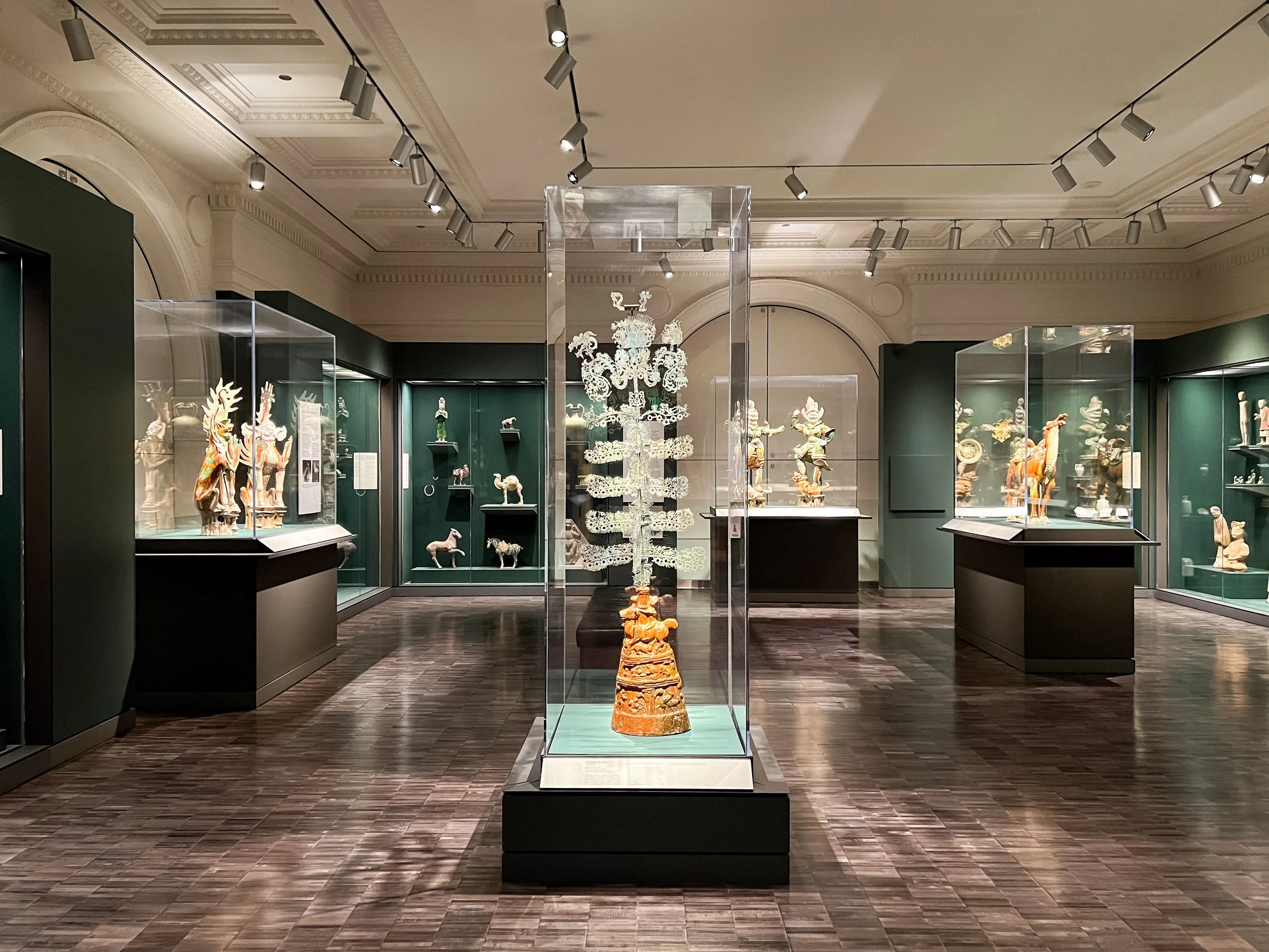 Museum display cases with painted pedestal bases of varying heights, built for clean sightlines and the protection of priceless Asian artifacts.