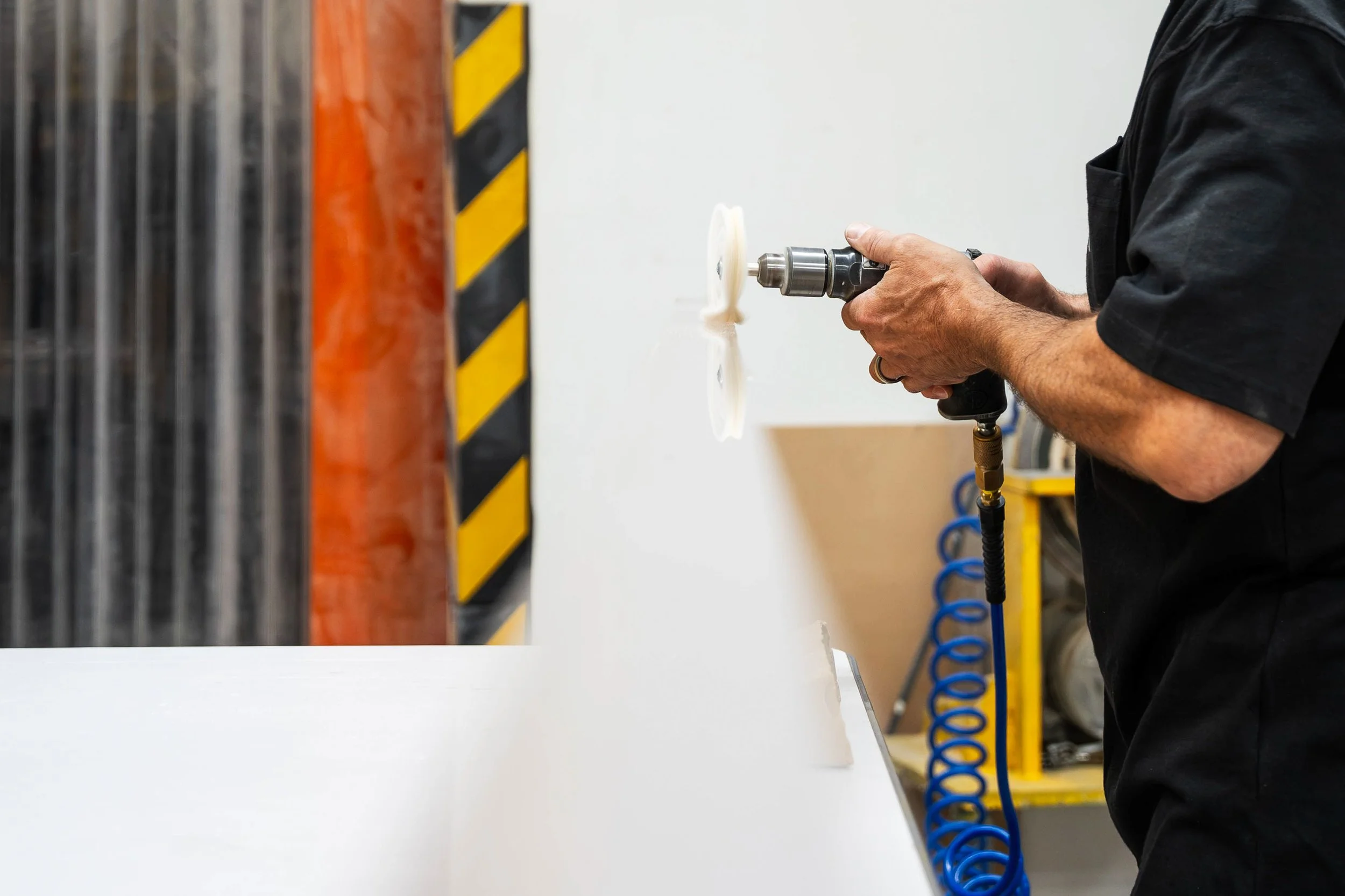 Fabricator using a buffing wheel to polish a 10 foot long clear acrylic edge.