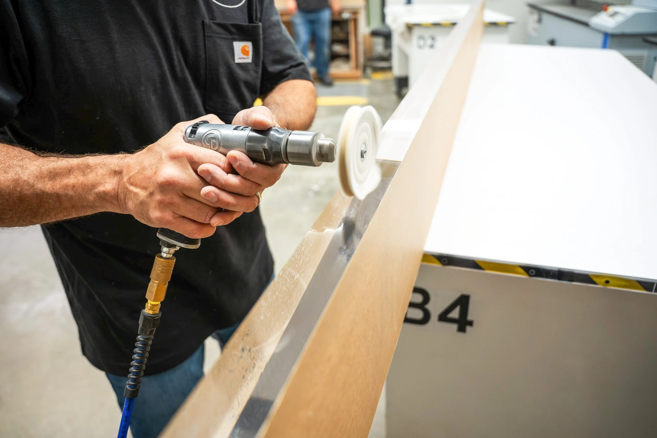 Large panel of 2" thick clear acrylic getting its edges polished by a plastic fabricator with a buffing wheel.