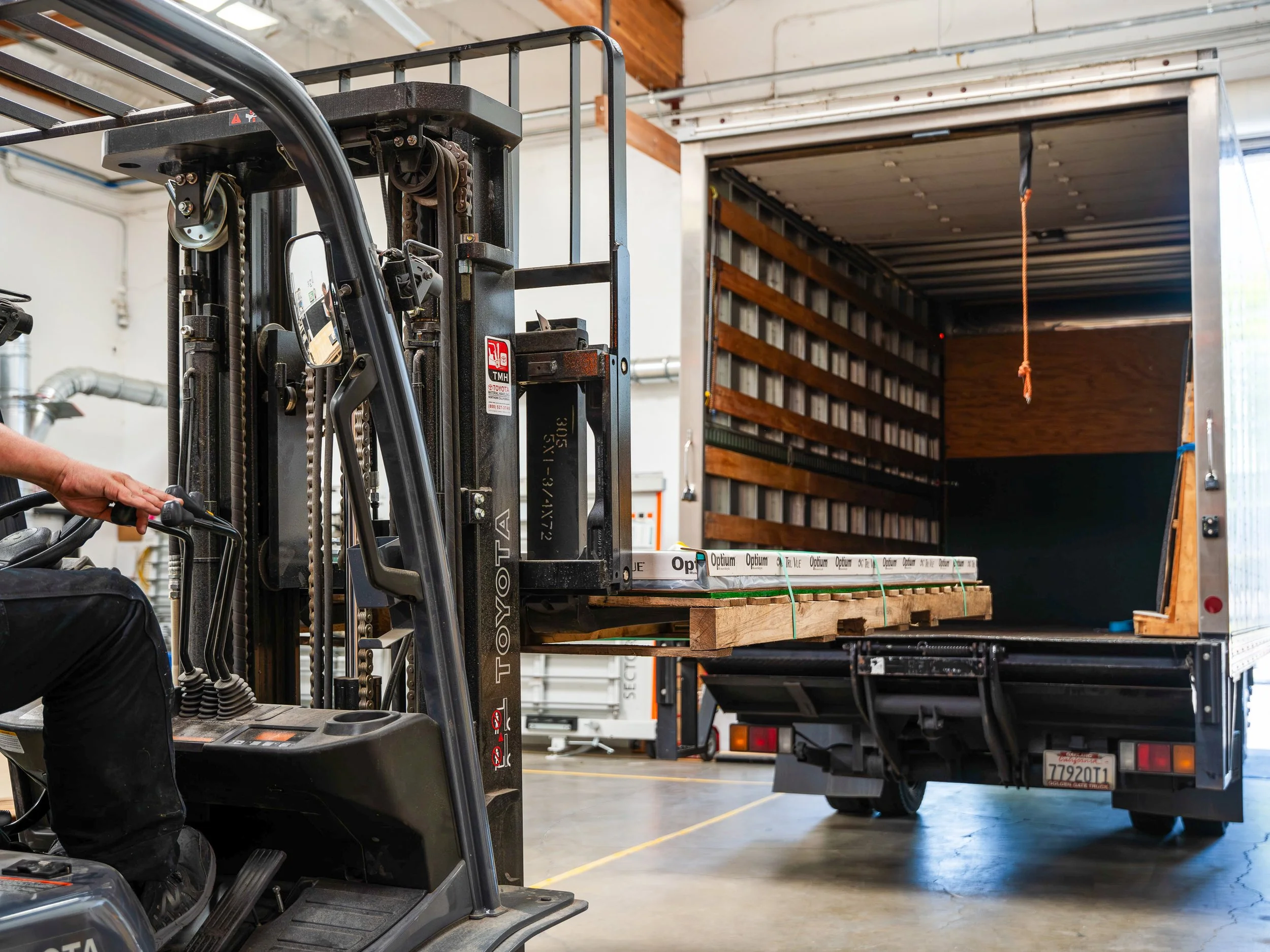 Forklift loading a pallet of acrylic sheets onto a truck for freight delivery and worldwide shipping.