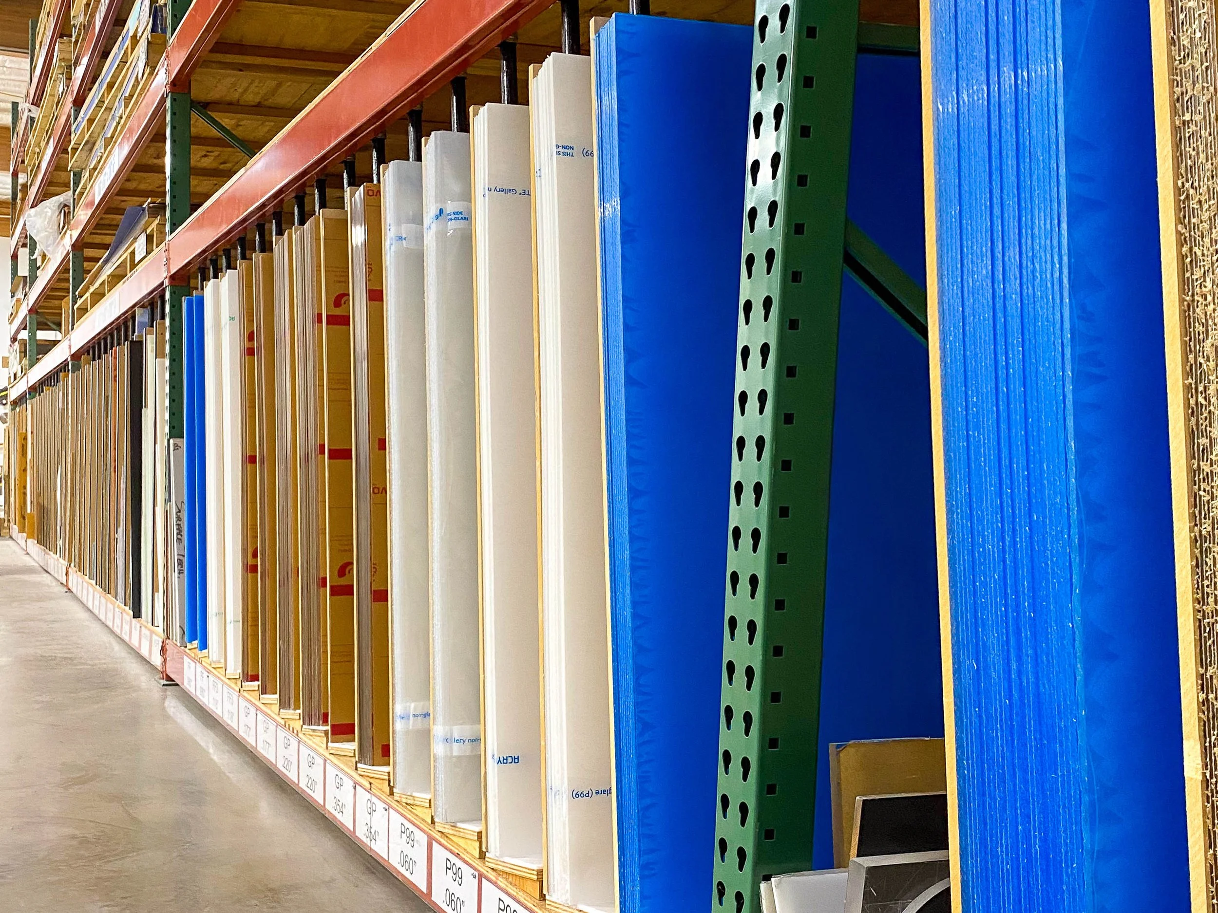 A large in-stock inventory of vertically stacked plastic sheets ready for fabrication.