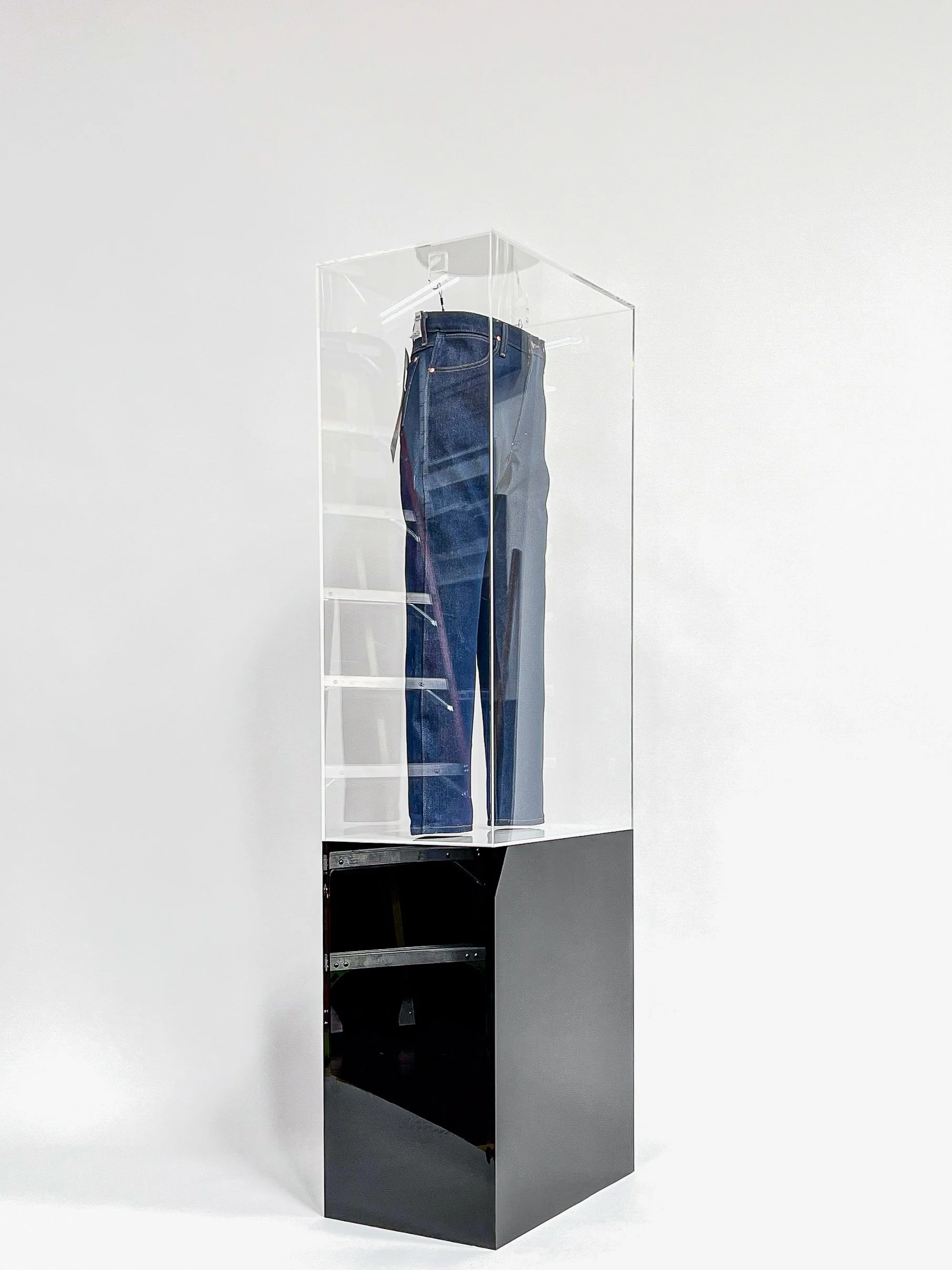 Bespoke clear acrylic display case matched with a custom gloss black pedestal plinth.  A unqiue hanging method was used to display and protect a pair of high value jeans. 