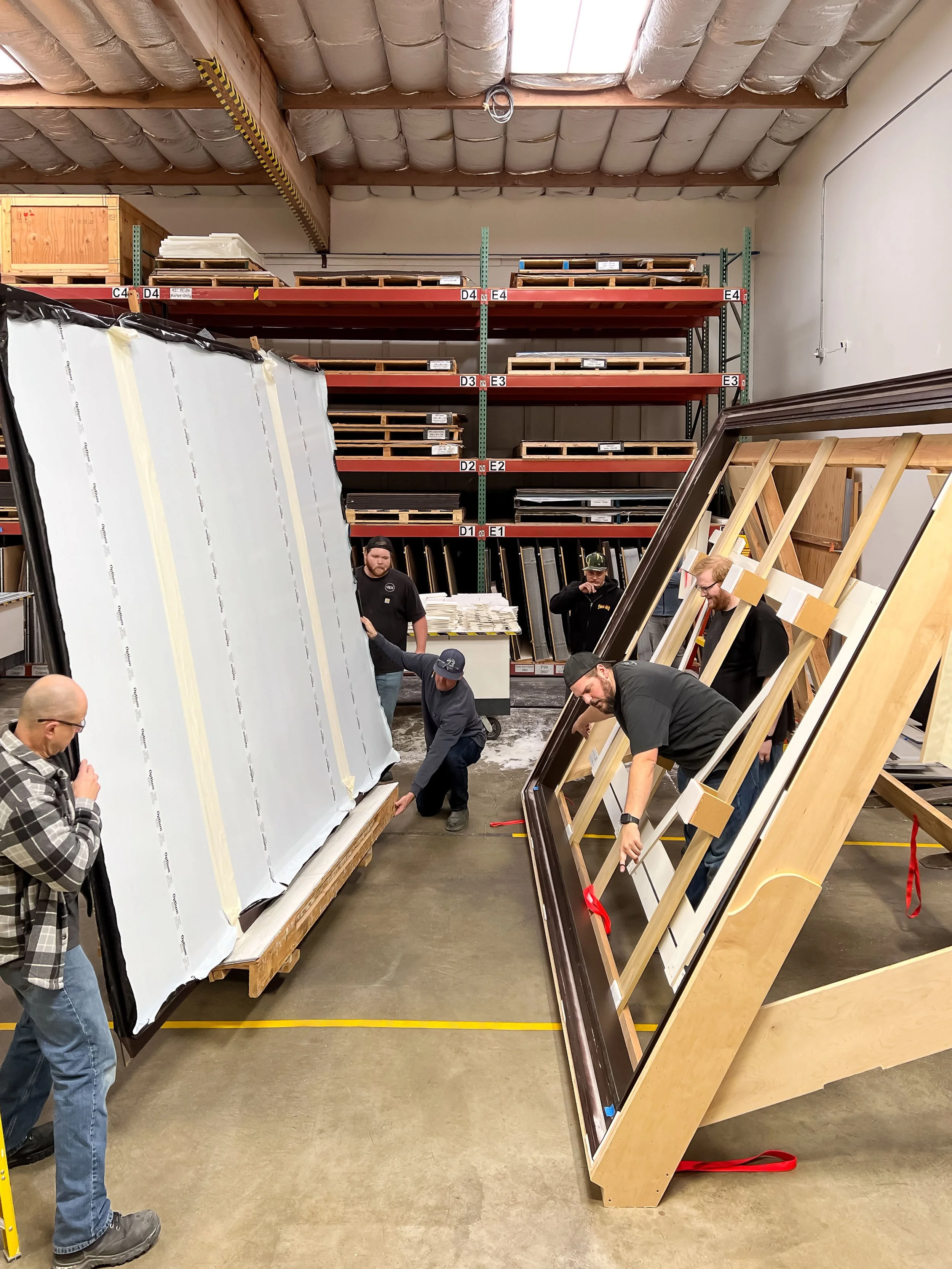 Fabricators fitting a double seamed Tru Vue Optium museum Acrylic Panel into an oversized wooden frame.