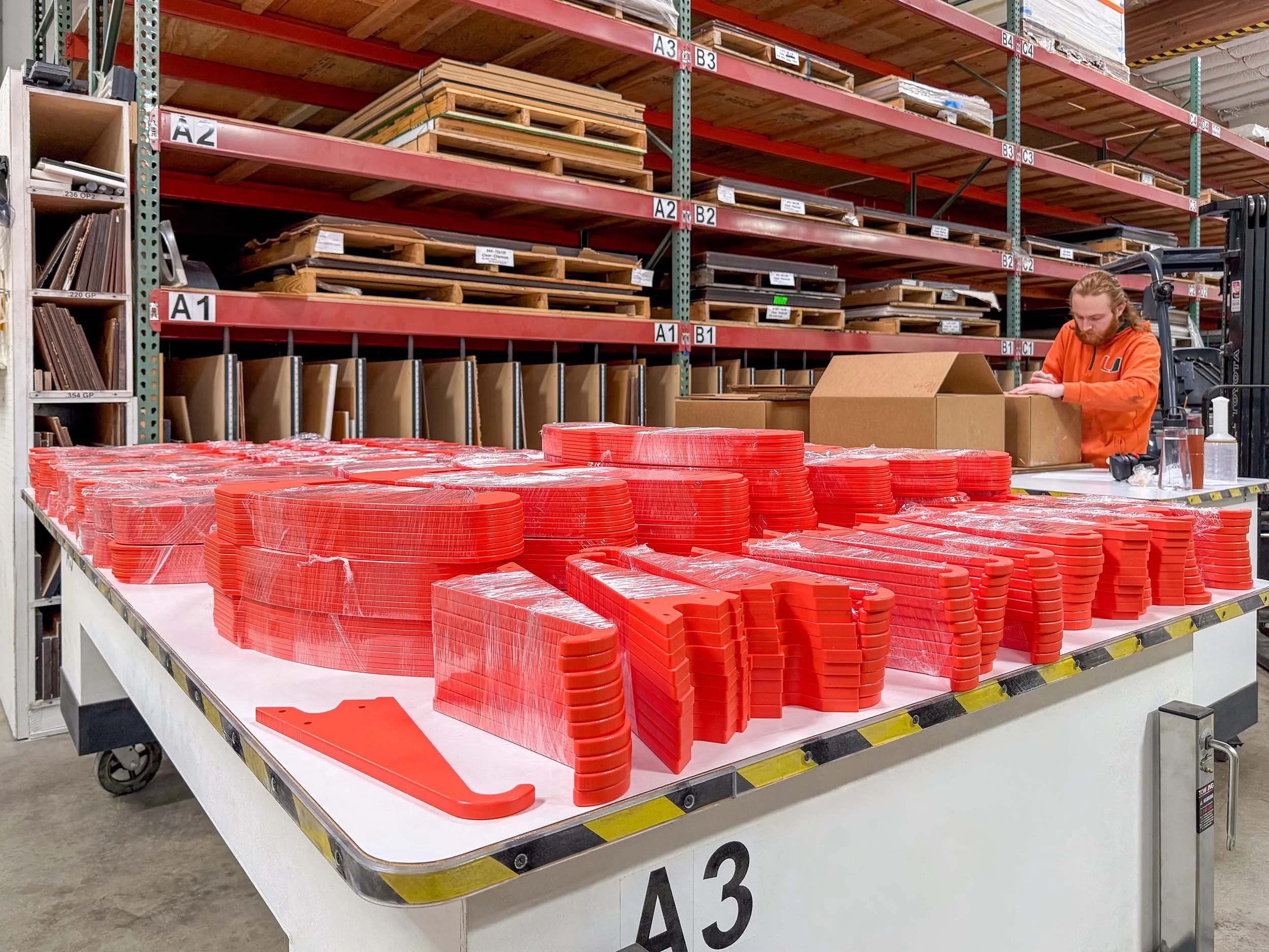 High-volume production run of machined red plastic parts staged on a fixture table for packaging and shipment from our San Francisco Bay Area shop