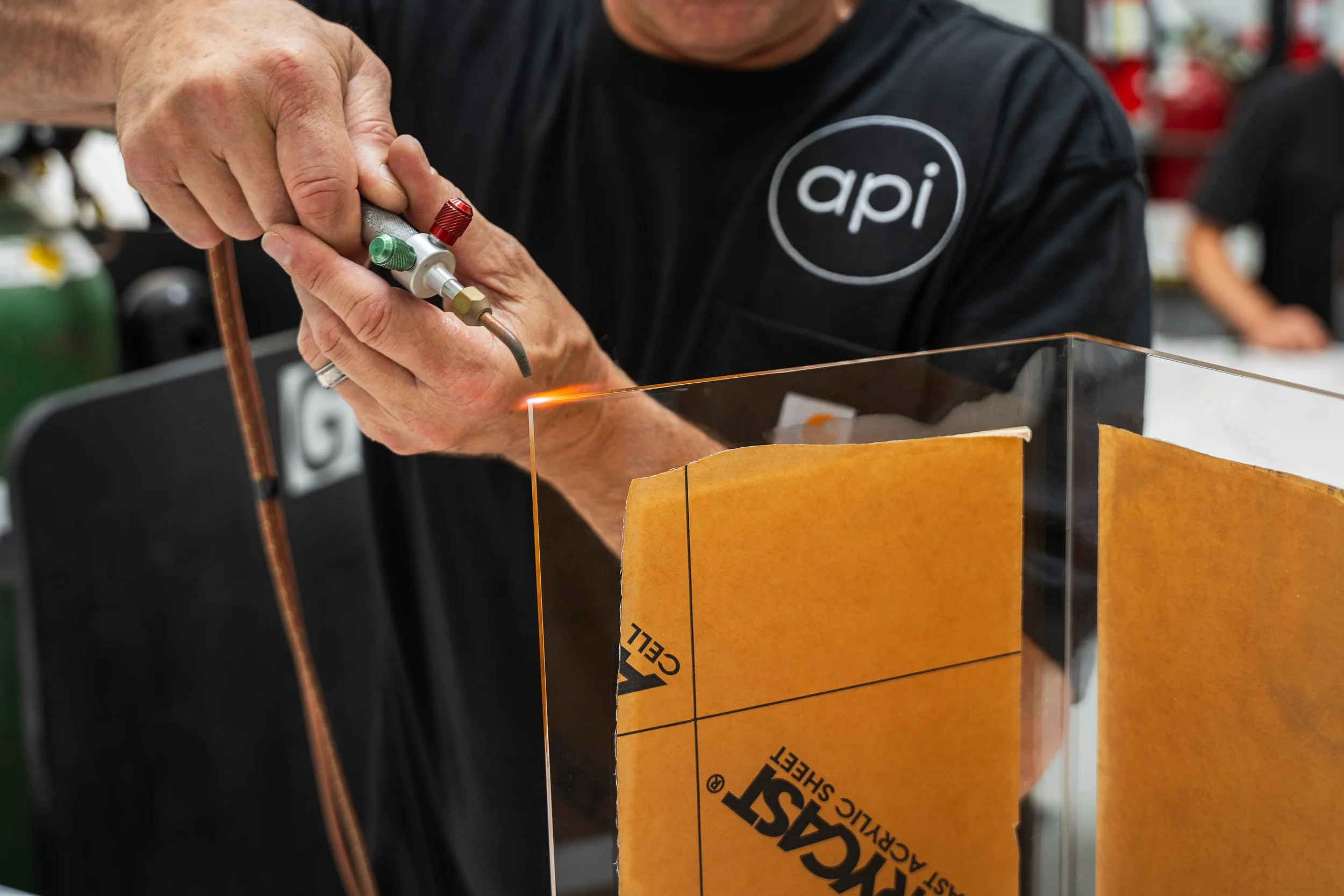 Acrylic fabricator flame polishing an edge of a glued acrylic assembly.