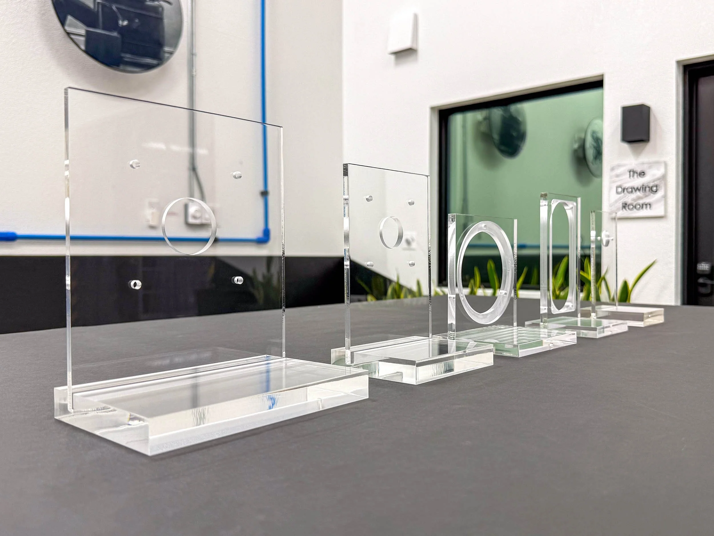 Prototype clear acrylic components staged to verify fit, hole patterns, and edge finish.