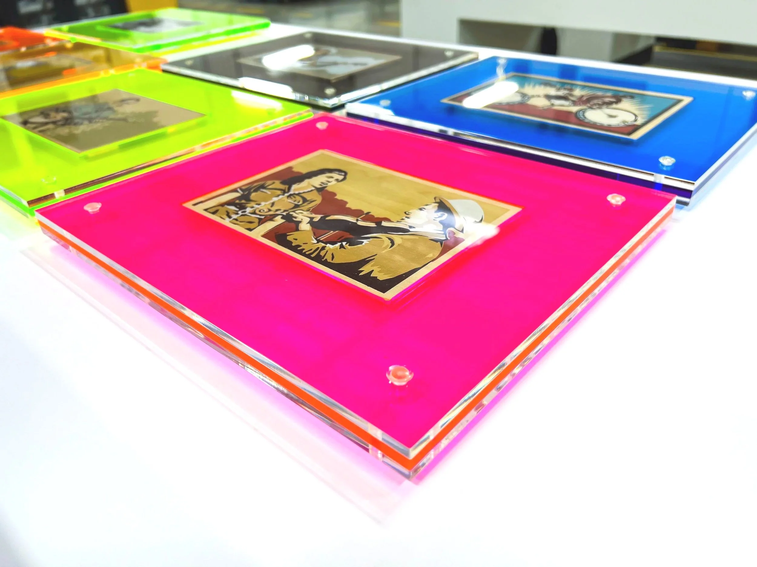 Several assemblies of clear and neon colored acrylic frames with artwork inside of them.