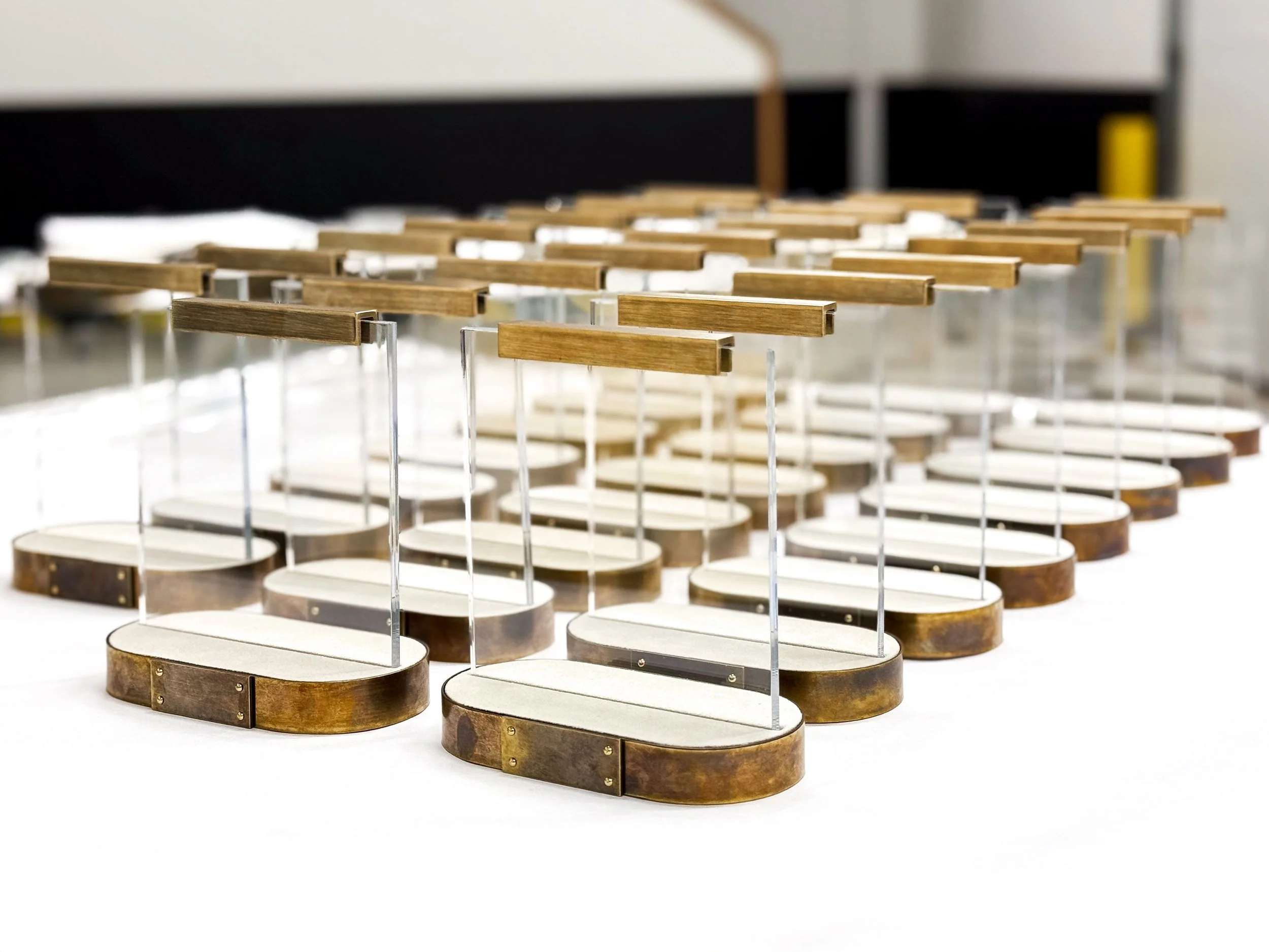 In shop fabrication snapshot of table tents made of antiqued brass metal, clear acrylic, mdf and suede.