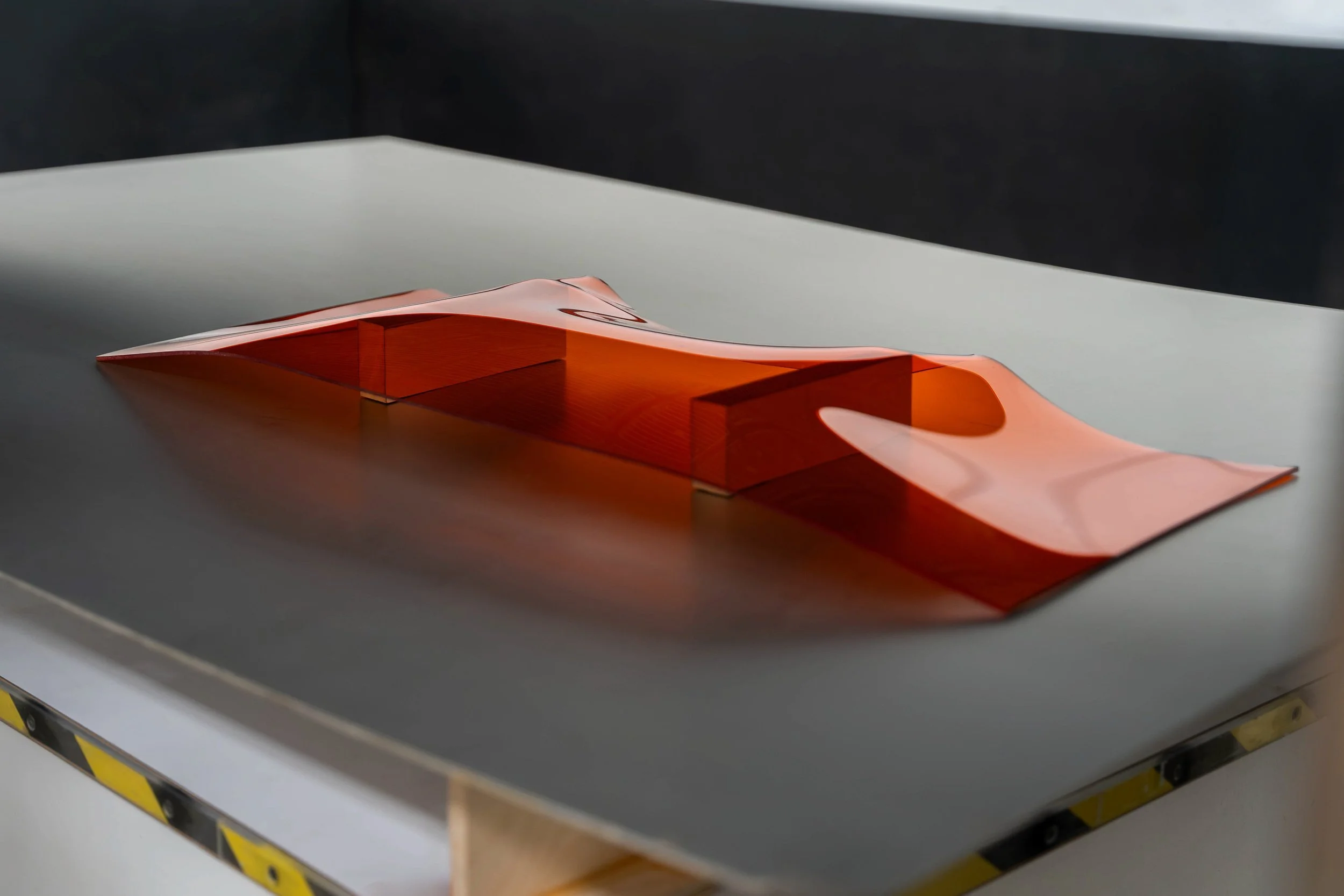 Transparent orange acrylic panel showing deflection during infrared thermoforming processing.