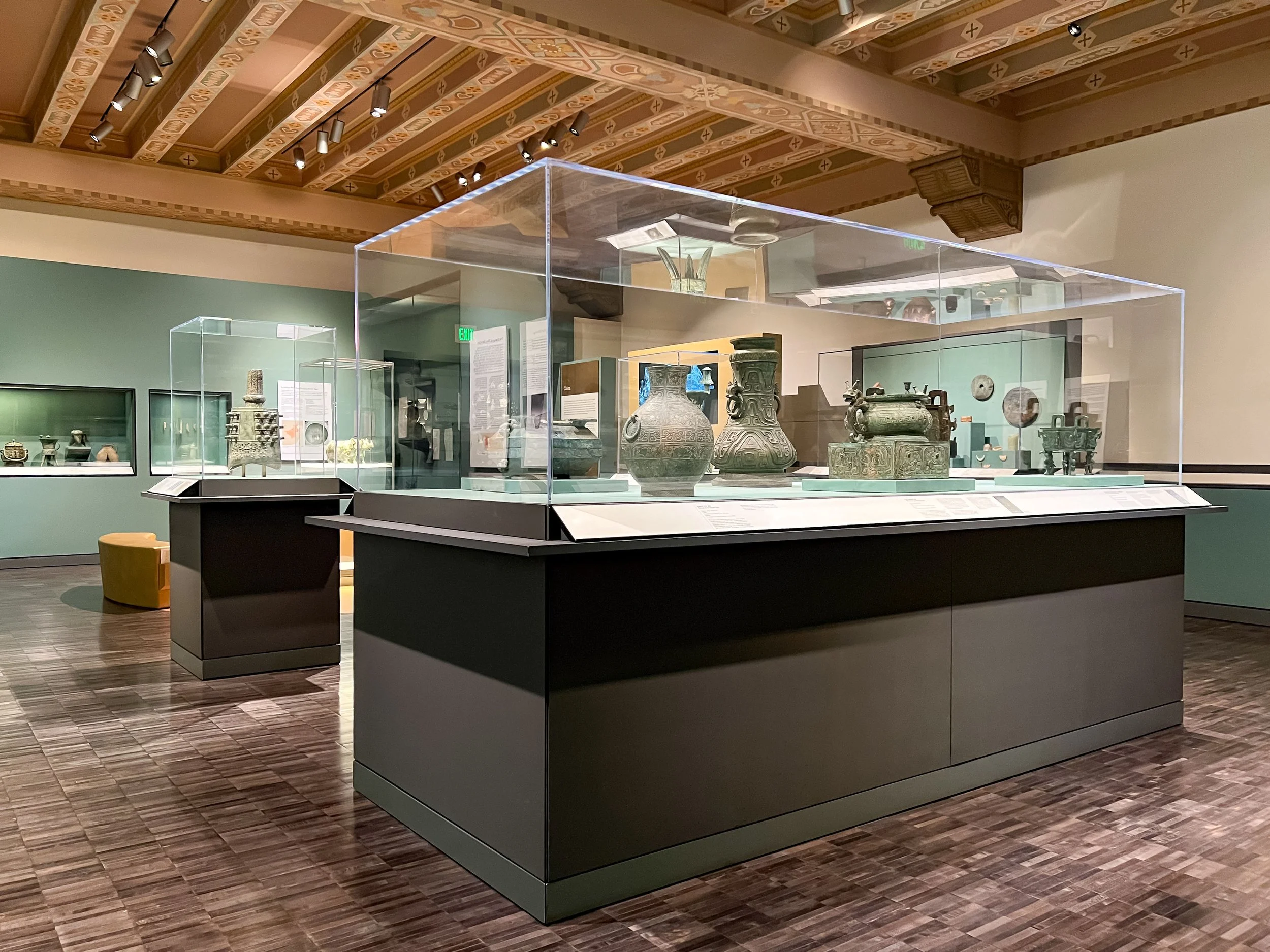 Oversized clear acrylic display cases on painted pedestals, displaying ancient artifacts.