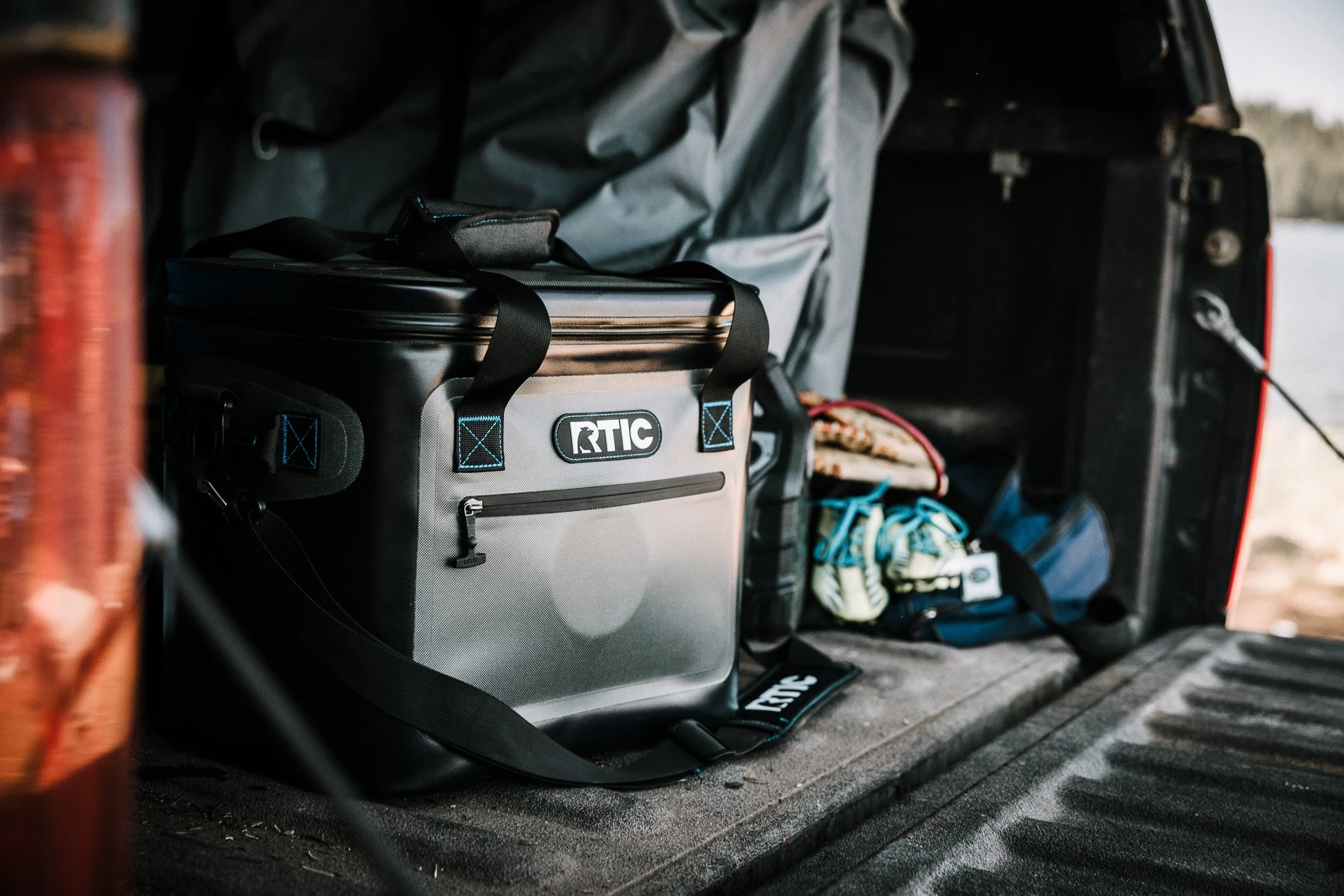 Cooler, gear, and supplies in back of a vehicle for outdoor or fishing trip.