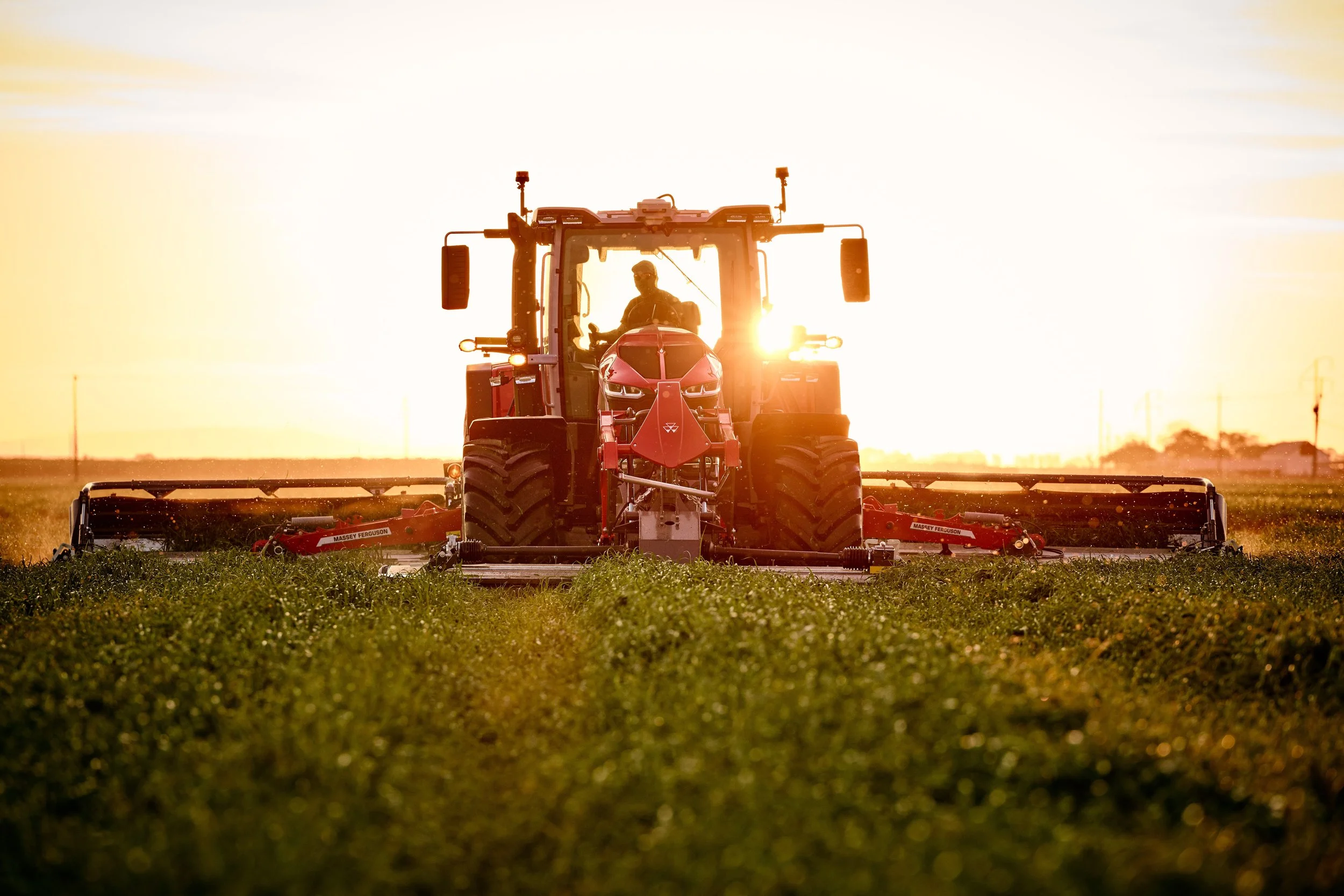 A tractor working on a farm during sunset.