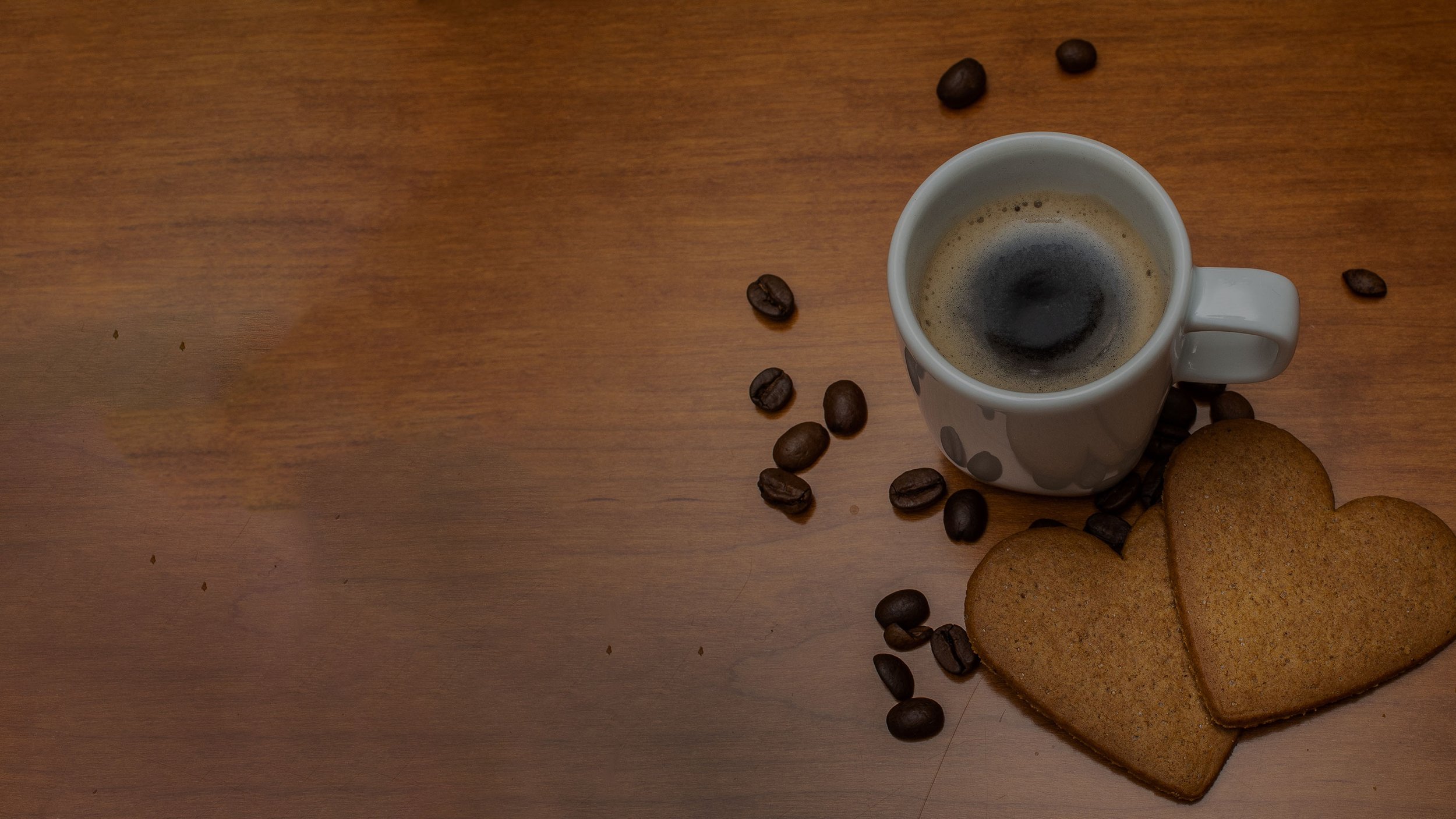 a cup of coffee, espresso beans and 2 ginger cookies