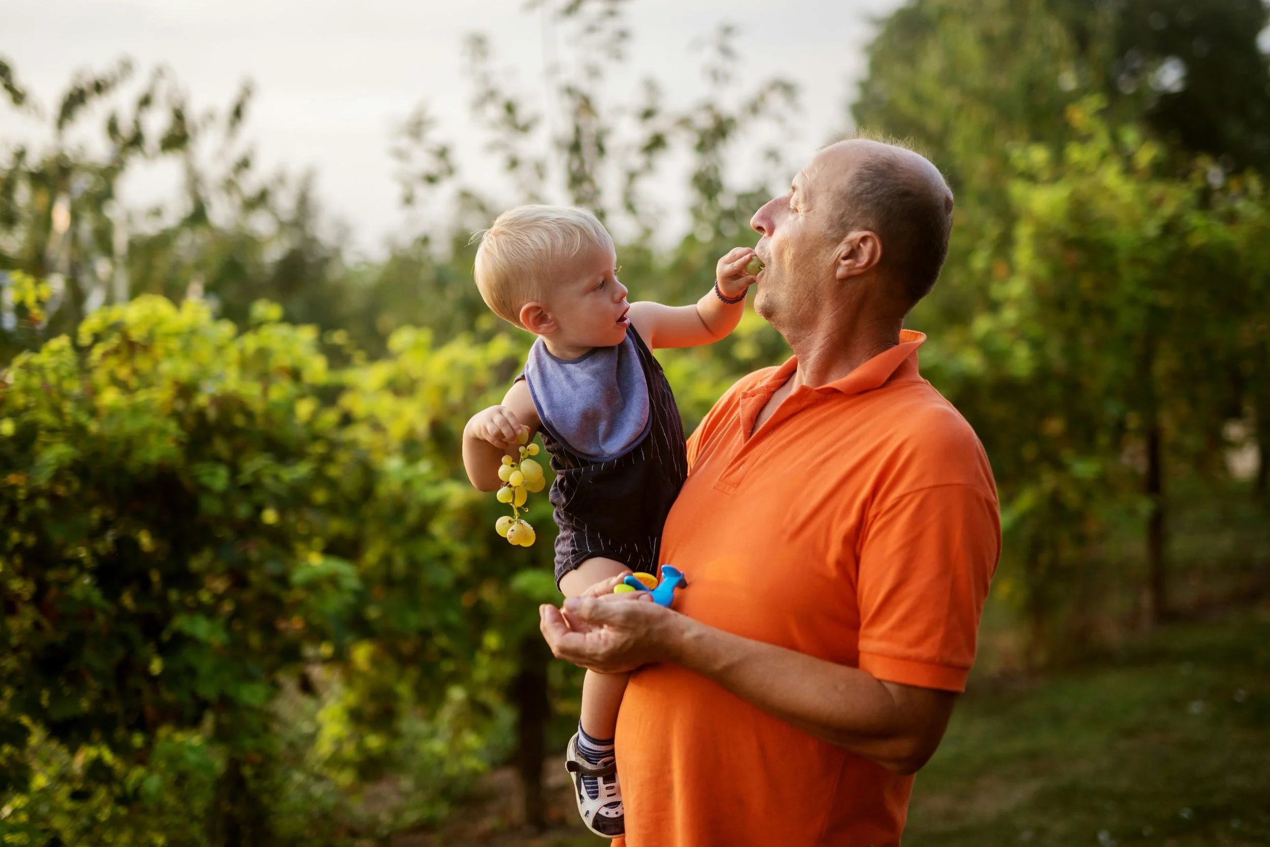Grandfather holding his grandchild, symbolizing the importance of preserving family stories for future generations.