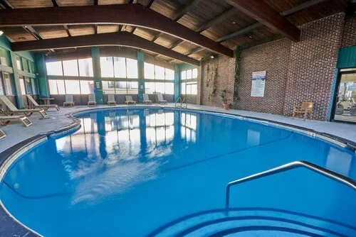 Indoor swimming pool with chairs and large windows