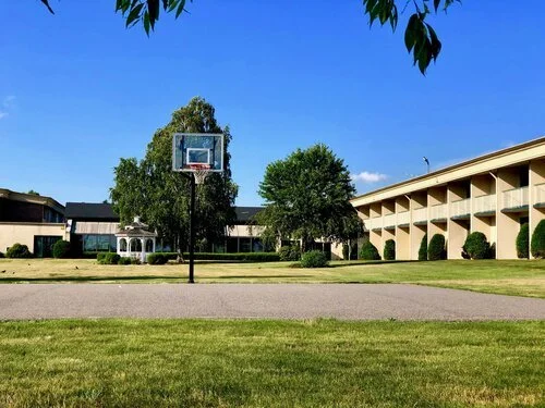 Outdoor basketball court with hoop and surrounding buildings