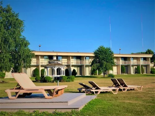 Lawn with lounge chairs near hotel building with balconies and gazebo