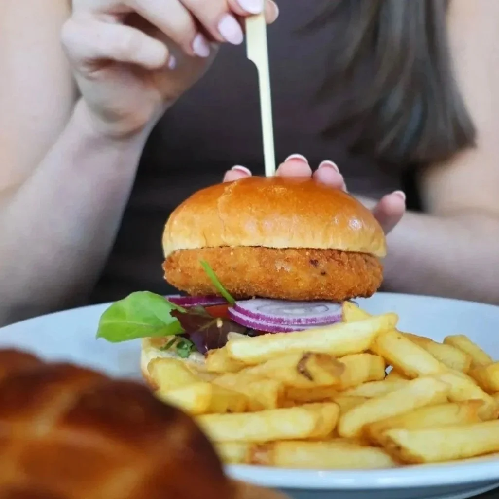 A plate of fish and chips with a lemon wedge, tartar sauce in a small black bowl, and a side salad.