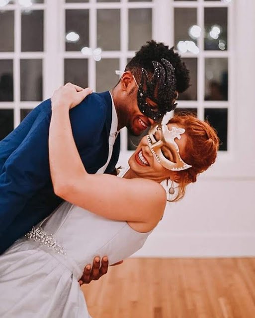 Bride and groom laughing together while wearing masquerade masks during a playful, fashion-forward wedding celebration at Springdale Station in Austin, Texas