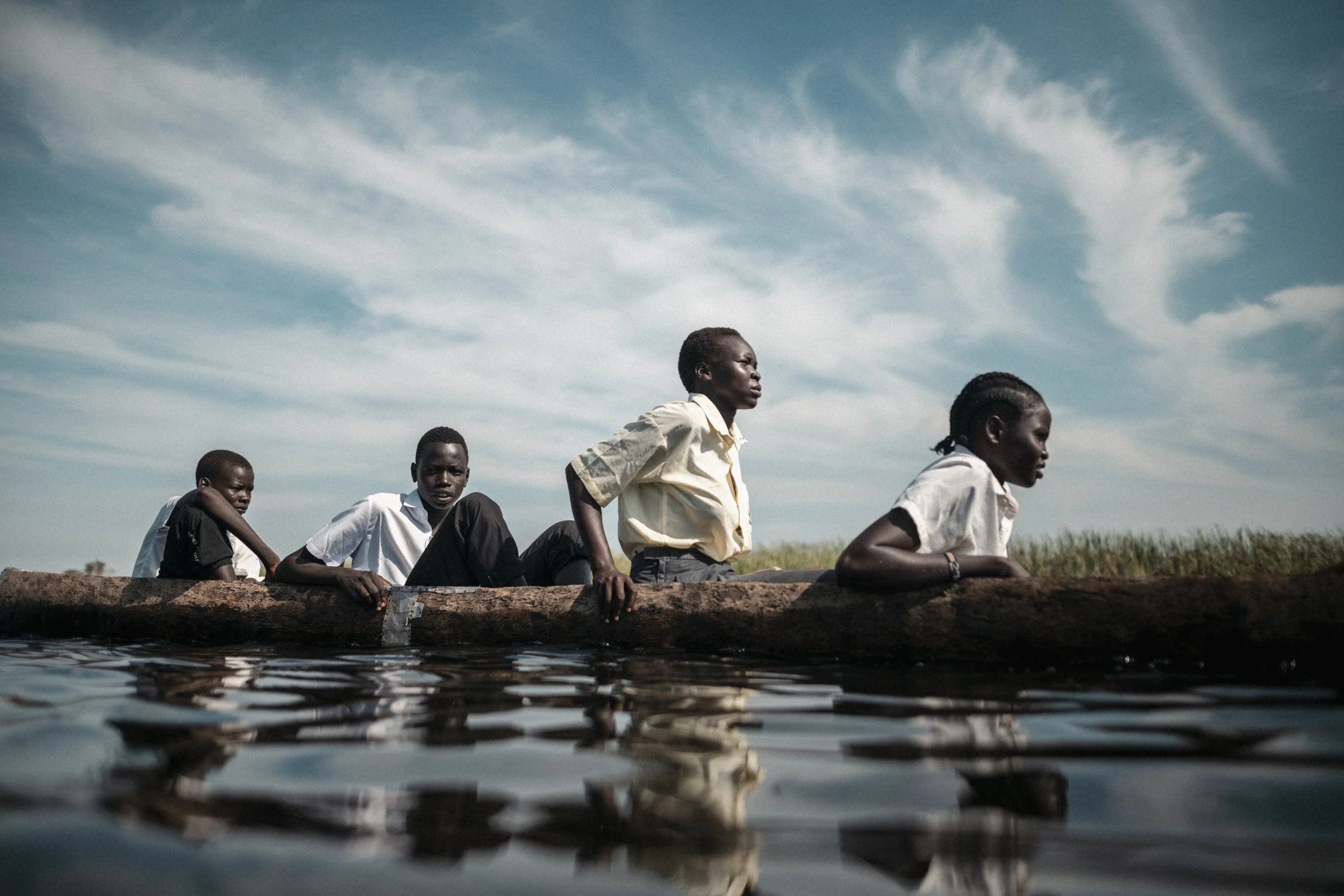Pupils travel by canoe to school. Flooding has turned routes once crossed on foot into waterways; without a place in a canoe, children may have to wade, swim or miss class.