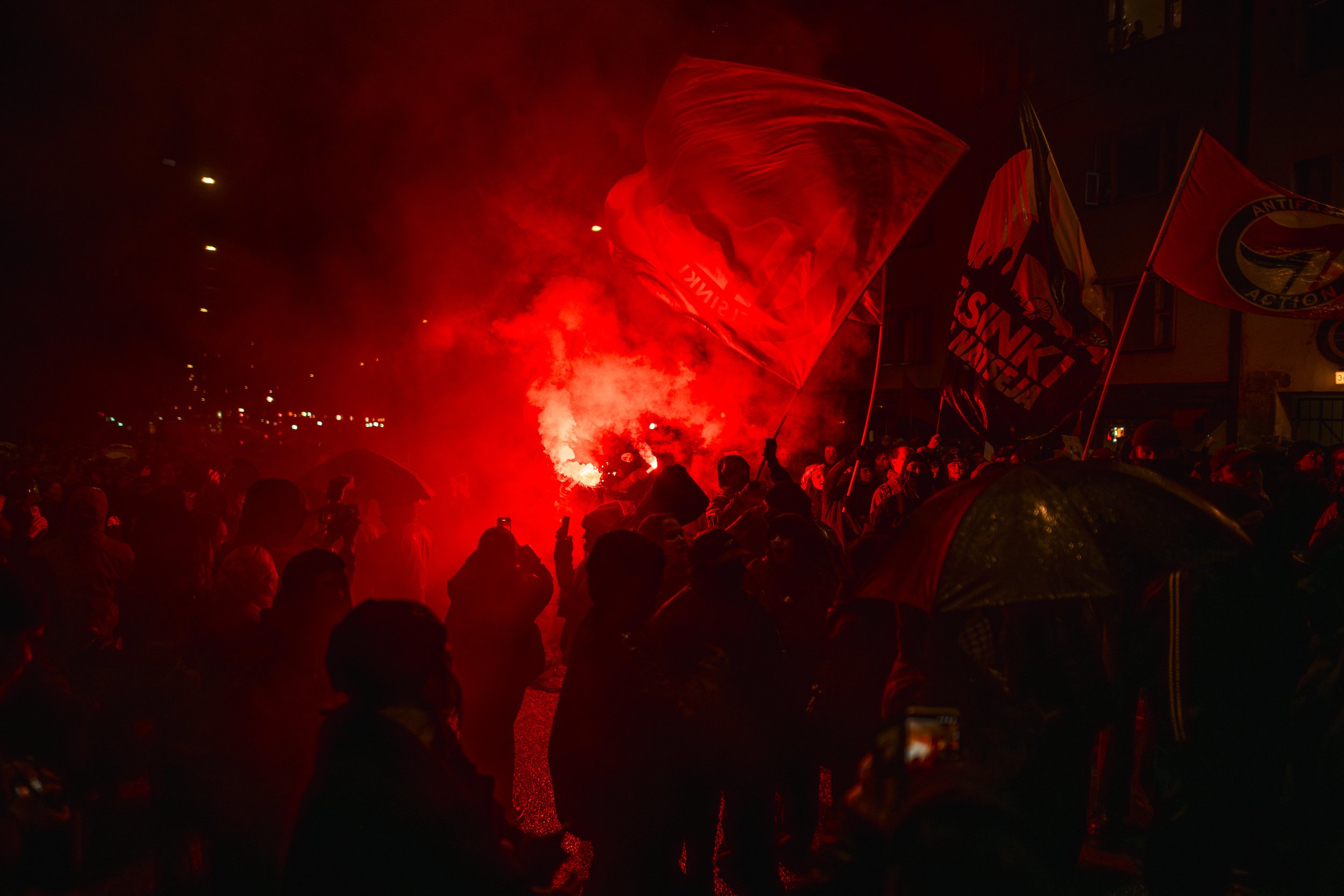Red flare smoke engulfs anti-fascist demonstrators during the Helsinki Without Nazis counter-demonstration in Töölö, Helsinki, on Finland’s Independence Day, opposing the far-right 612 torch march.