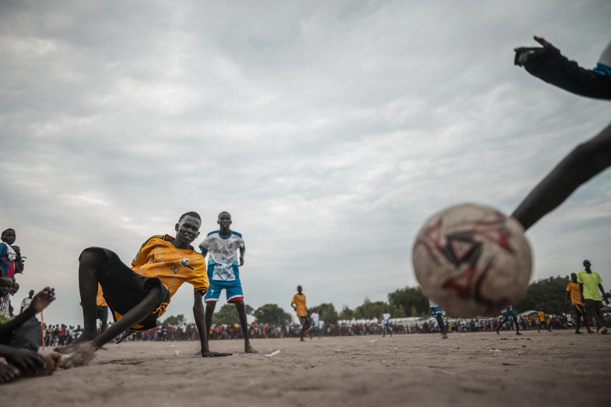A Sunday football match draws a crowd in Paguir. With no stands or barriers, the spectators form the boundary of the pitch.