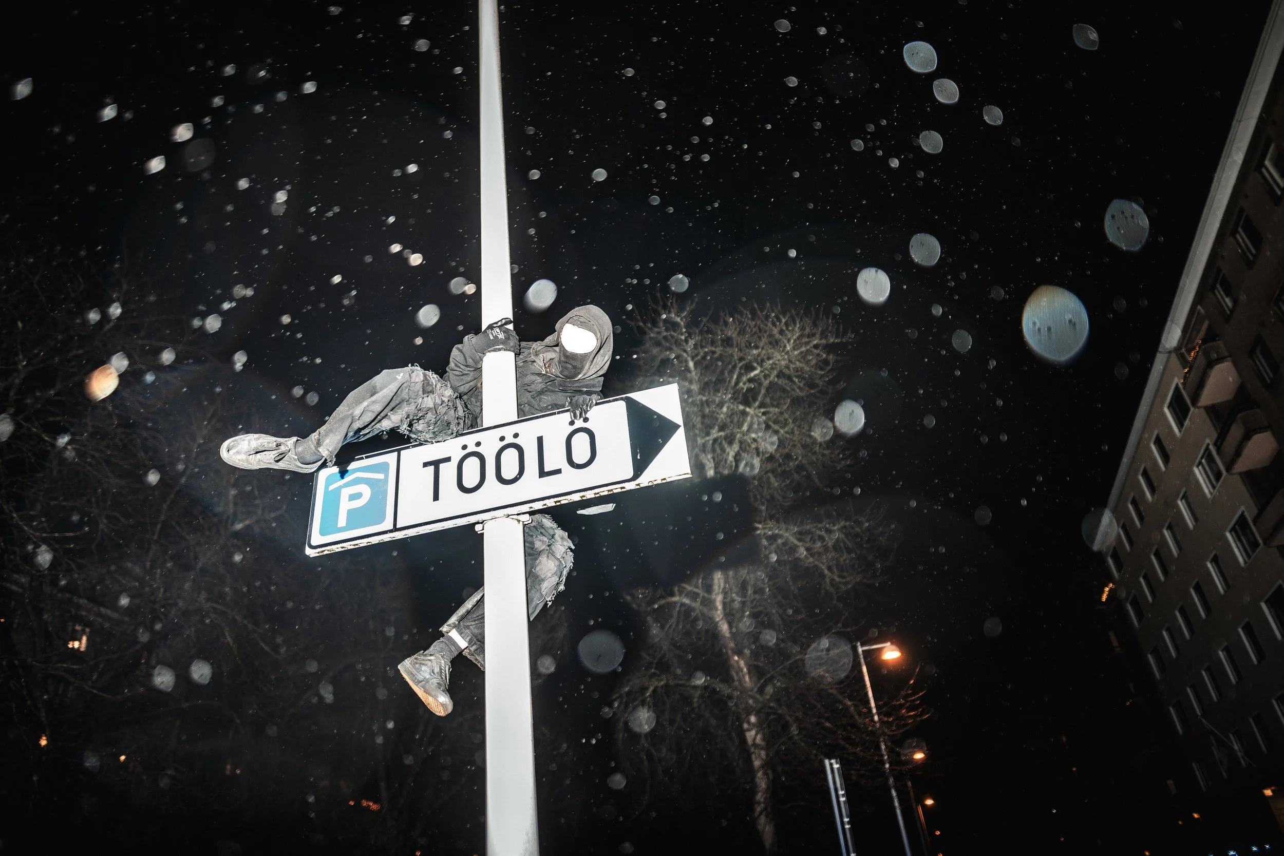 A demonstrator climbs a street sign during the Helsinki Without Nazis rally on Finland’s Independence Day. The event counters far-right marches like the 612 torch procession from Töölöntori, and Töölö has become a symbolic focal point where the two d