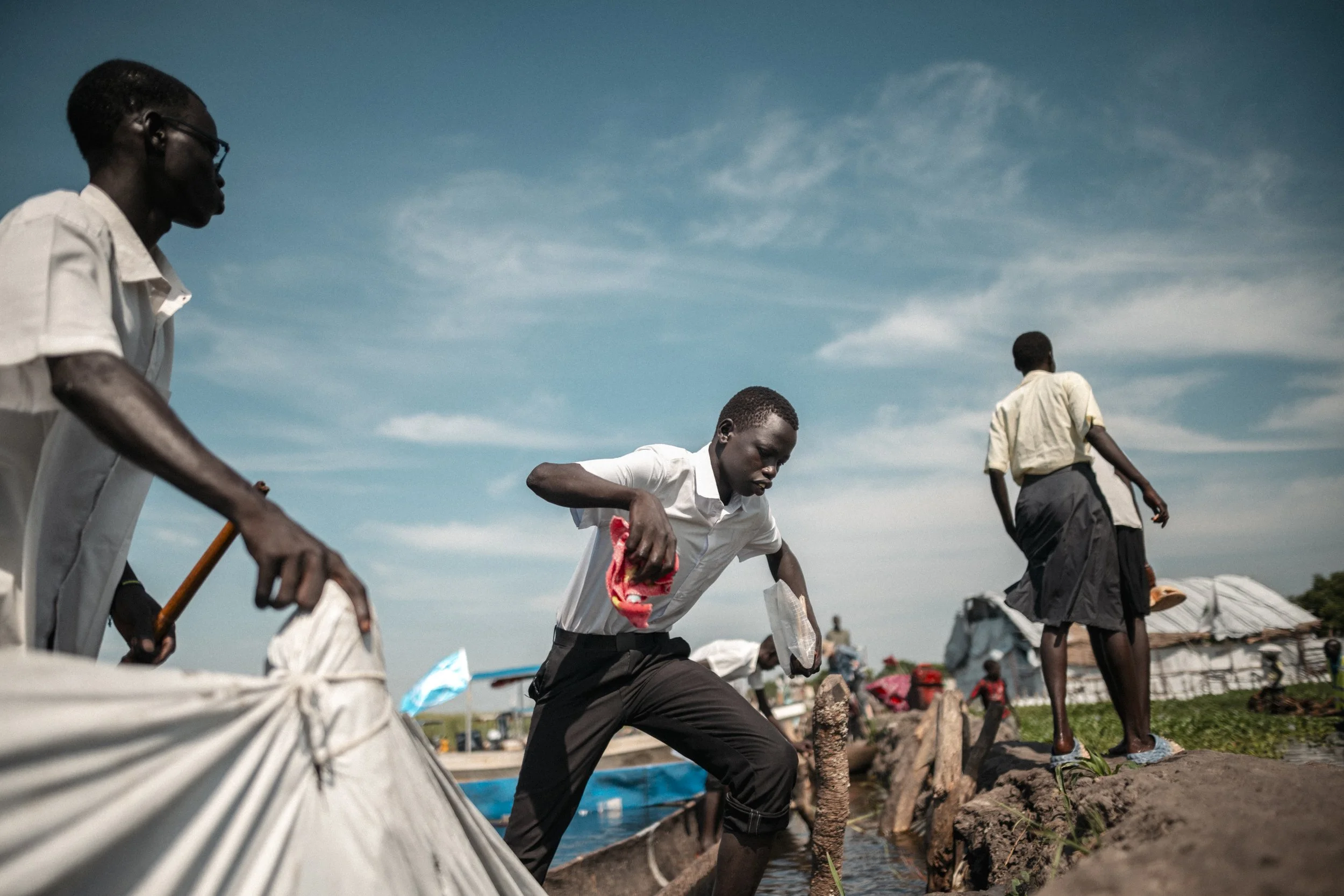 Pupils step from a canoe onto the dyke as they arrive in Paguir for school. There is no scheduled school boat, so many depend on finding space in a passing canoe.