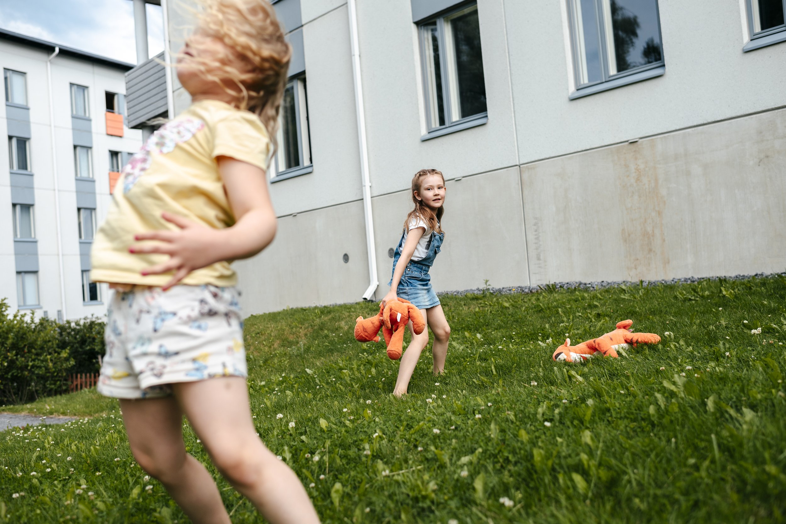 Lucia Hankiala, 6, plays in the yard of an apartment block with two Tikru tigers; her sister Sofia, 5, in the foreground. Tikru has been Lucia's bedtime toy since she was a baby, and helped her through years of affective seizures. Pirkkala, July 2020