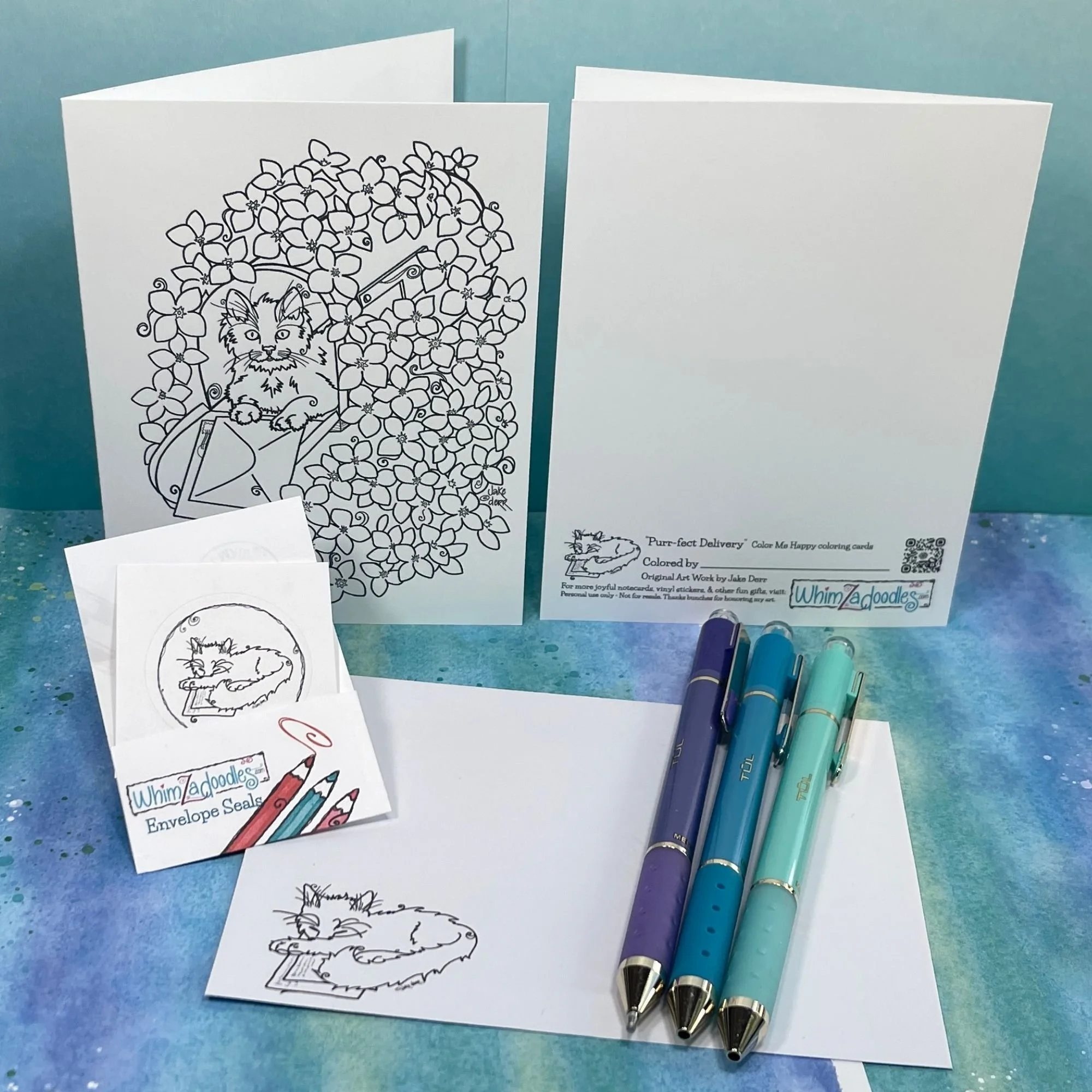 kitten coloring card, envelope, seal, and gel pens arranged on teal surface ready for use