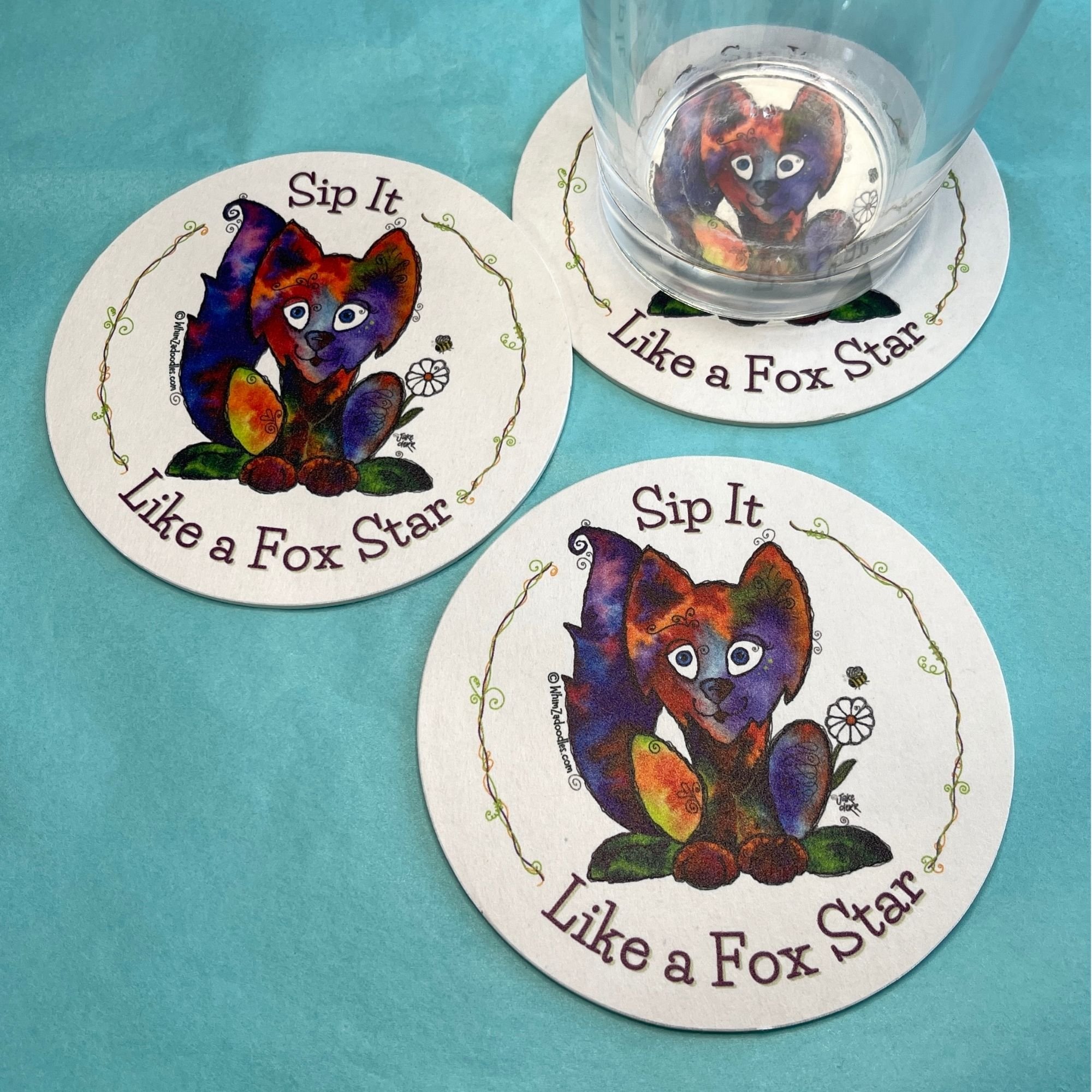 Glass of beverage resting on fox-themed drink coaster showing absorbent surface and real-life use on tabletop