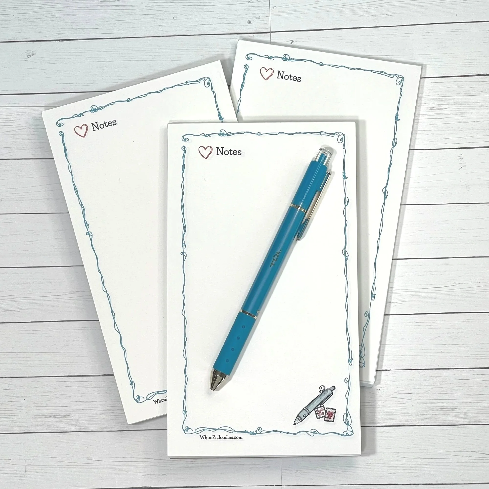 Tall notepad with whimsical teal doodle border and small pen with stamps illustration in the bottom corner on a clean white page