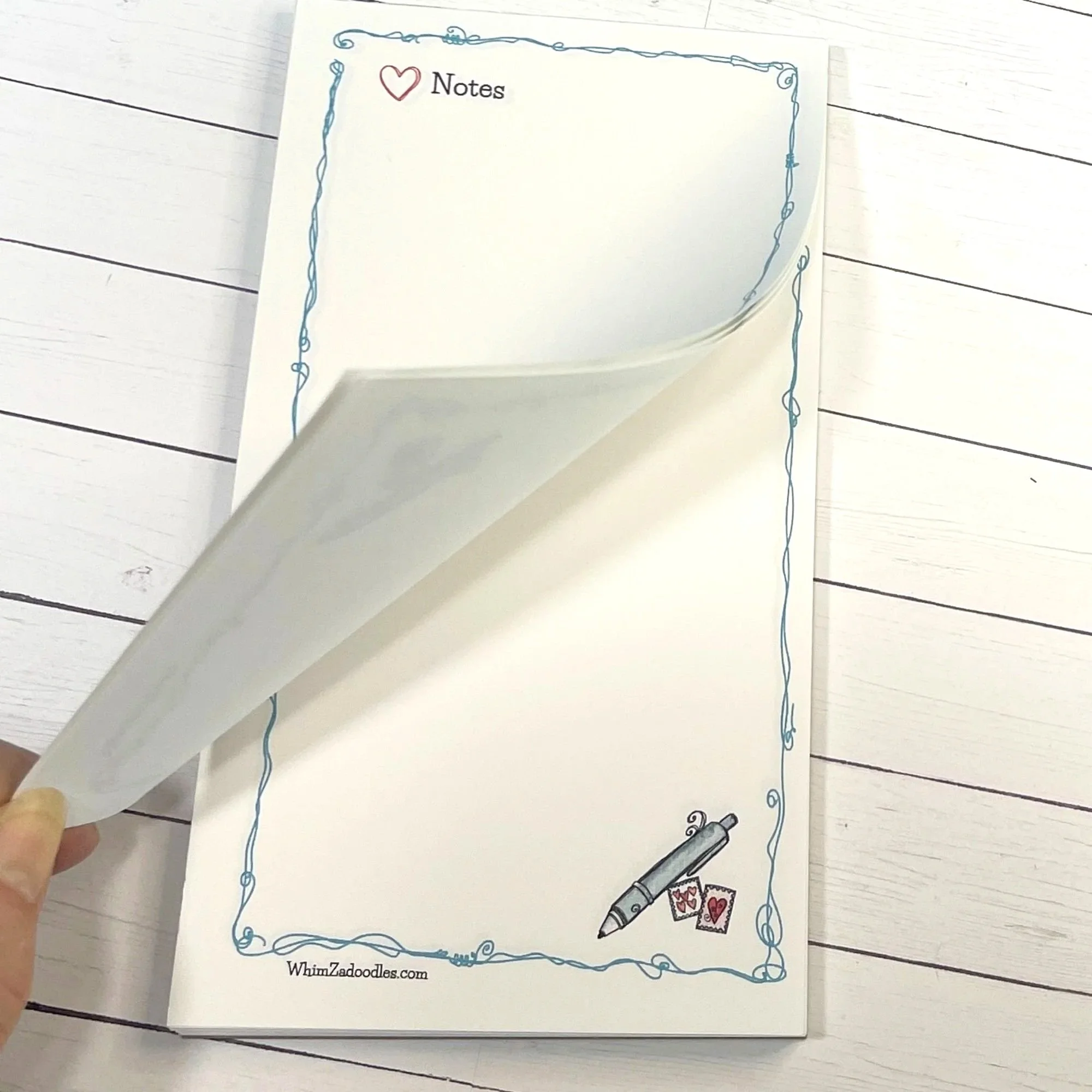 Close view of heart notes notepad with a page lifted showing tear-away design and neatly stacked sheets underneath