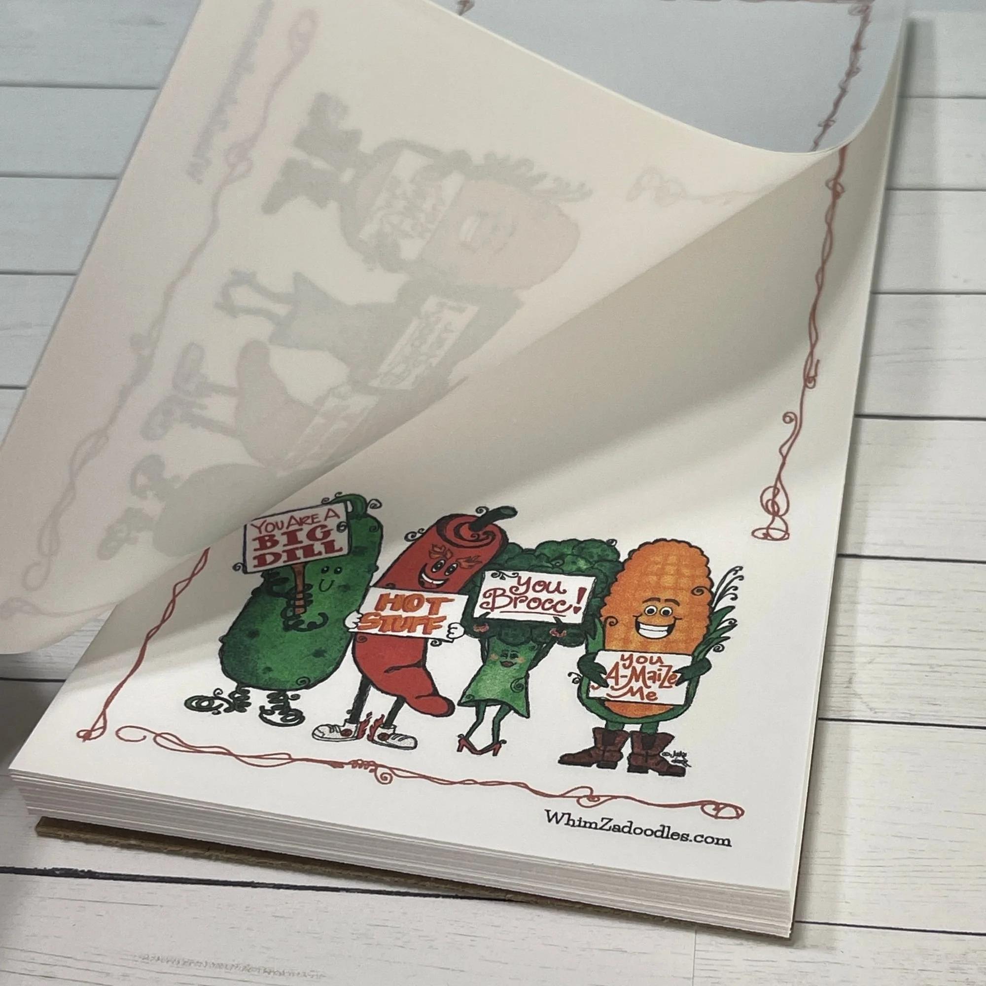 Close-up of Cultivating Kindness Crew notepad with lifted page showing paper quality and texture