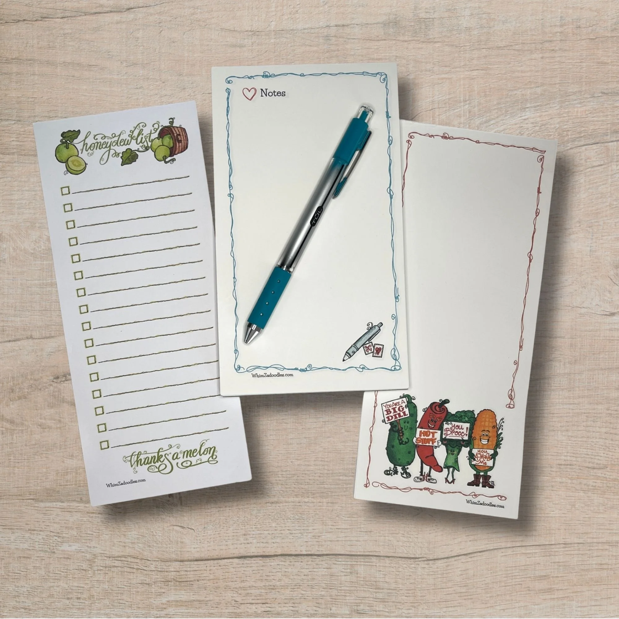 Three WhimZadoodles notepads displayed together featuring honeydew list, heart notes, and kindness crew designs with colorful whimsical artwork