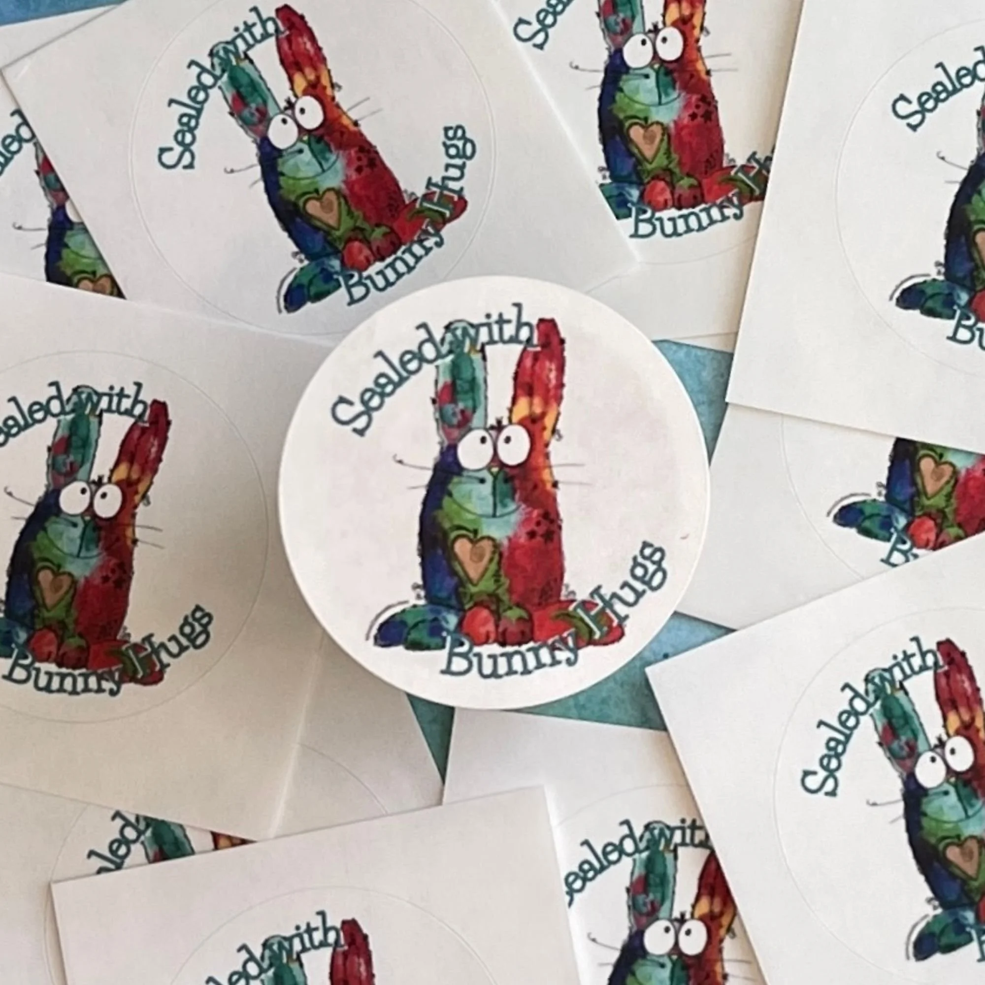 Close-up of Bunny Hugs envelope seal showing bright watercolor bunny with stitched heart and playful doodle details