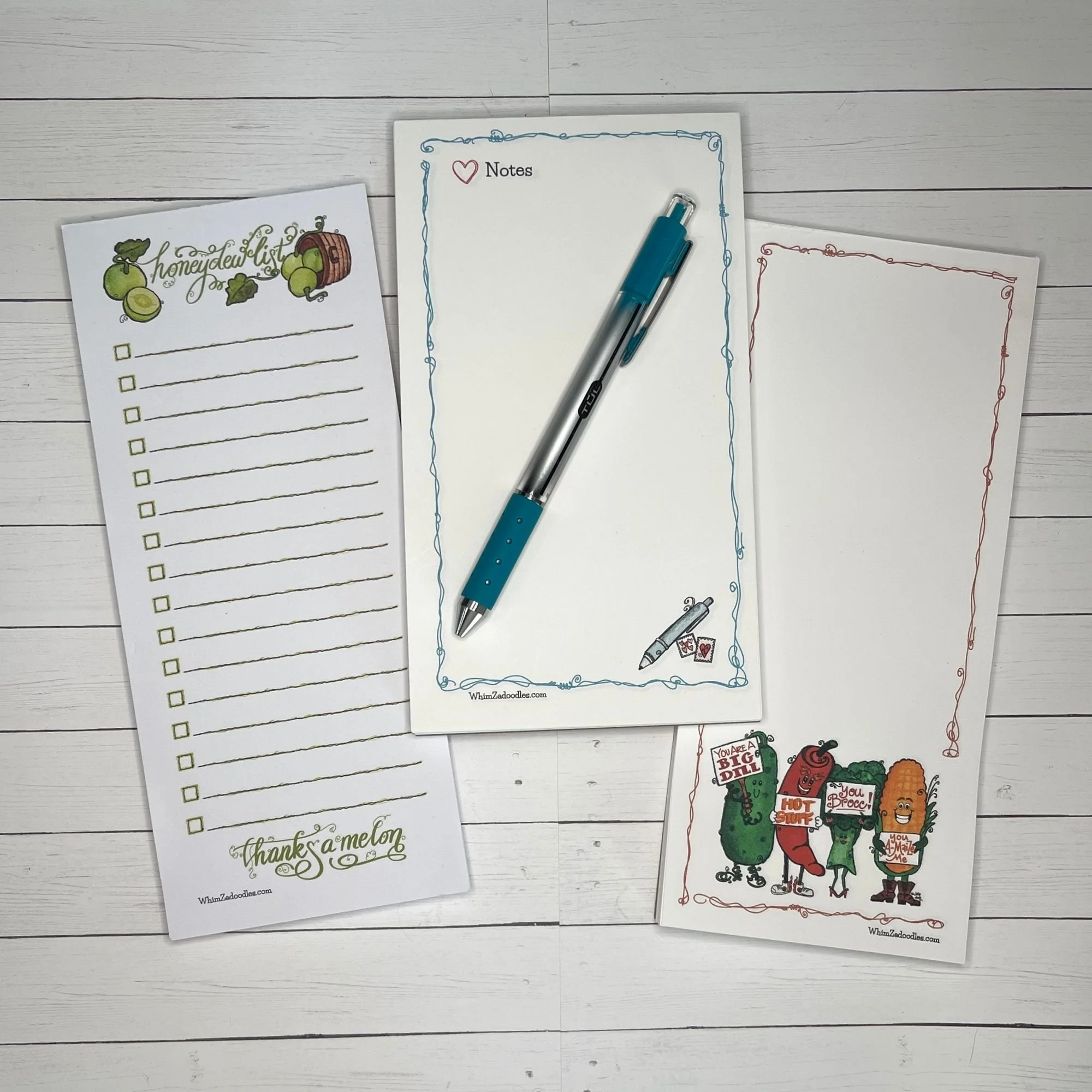 Three coordinating notepads grouped together featuring playful designs and soft watercolor tones for cheerful note taking