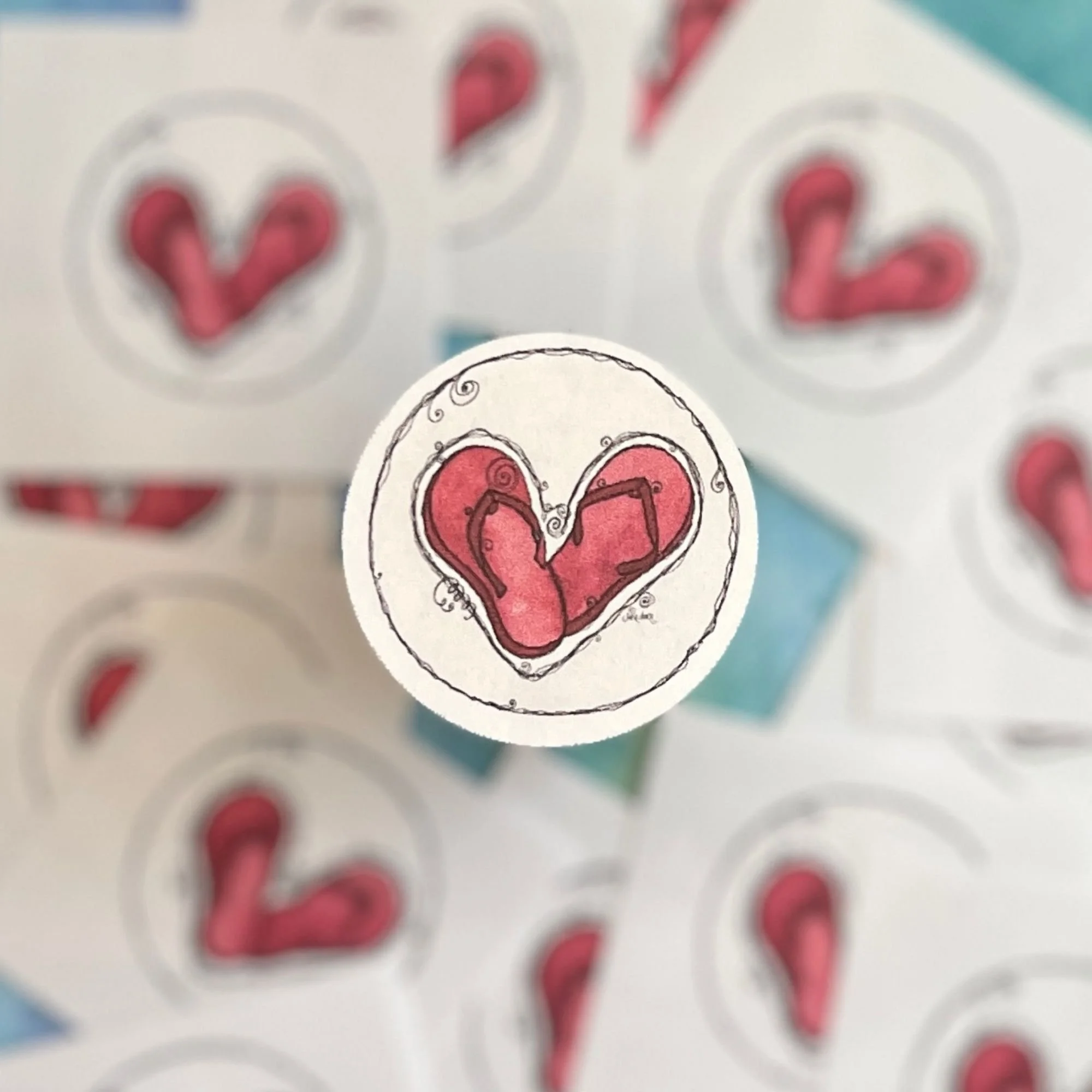 Close-up of Flip Flop Love envelope seal showing red watercolor sandals forming a heart with curly doodle accents