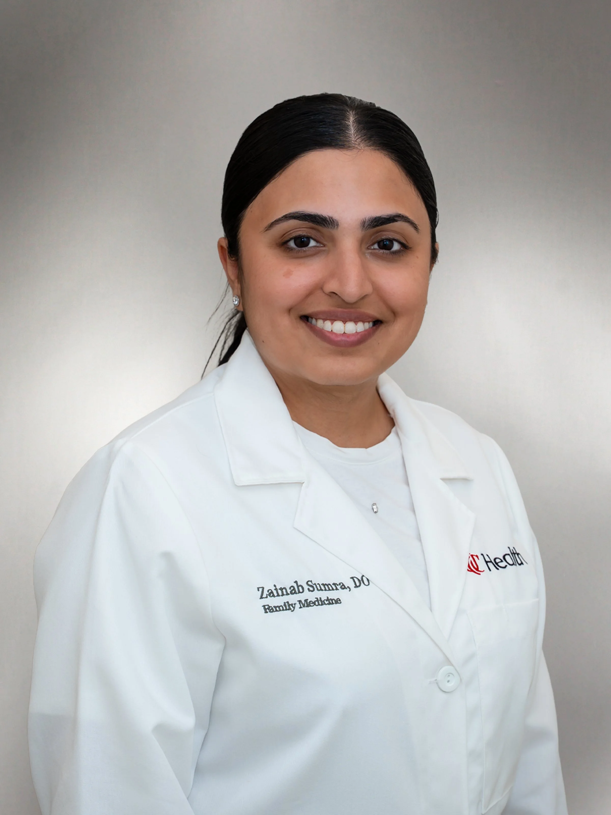 Dr. Zainab Sumra wearing a white lab coat in a professional headshot.