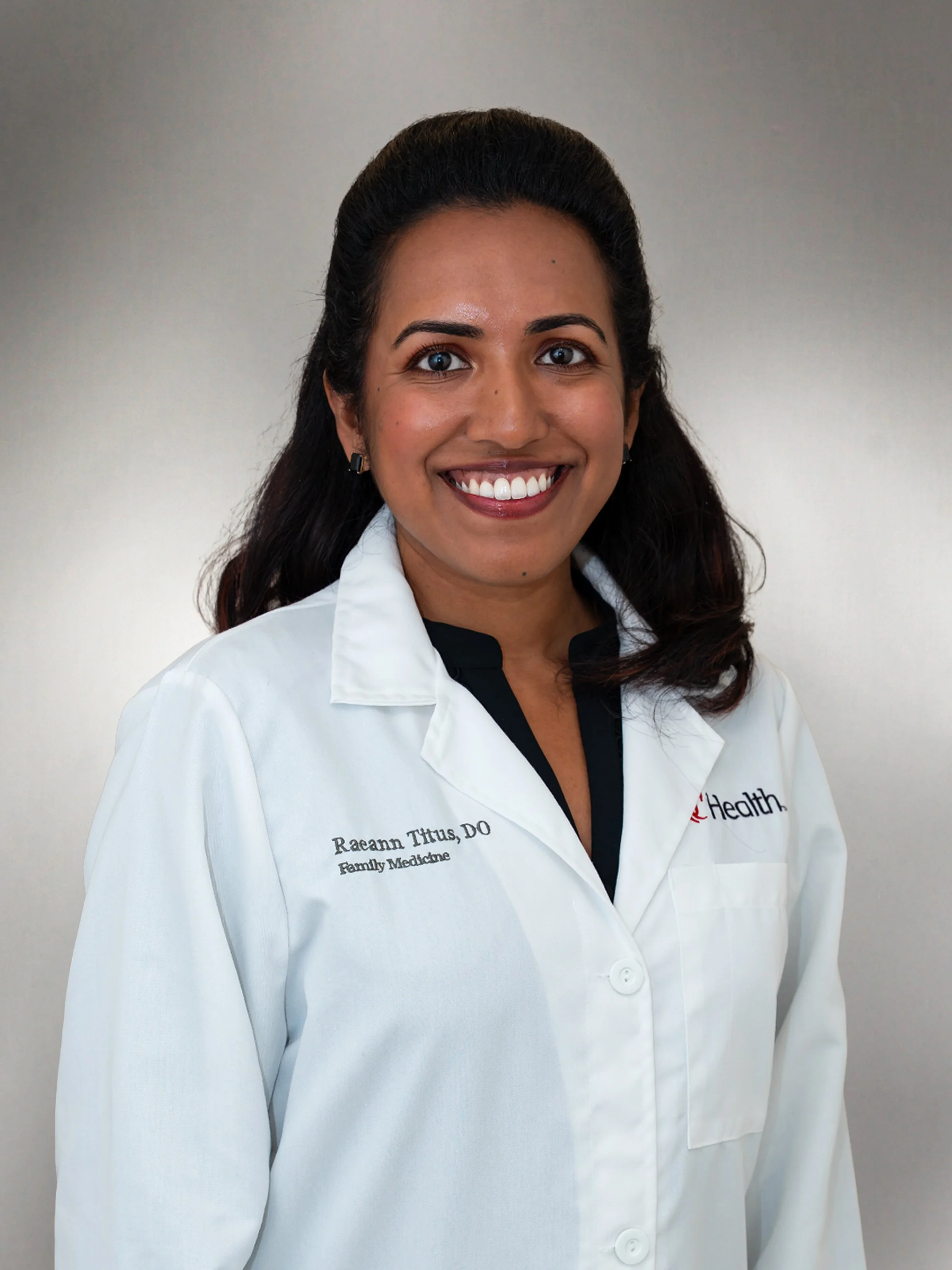 Dr. Raeann Titus wearing a white lab coat in a professional headshot.
