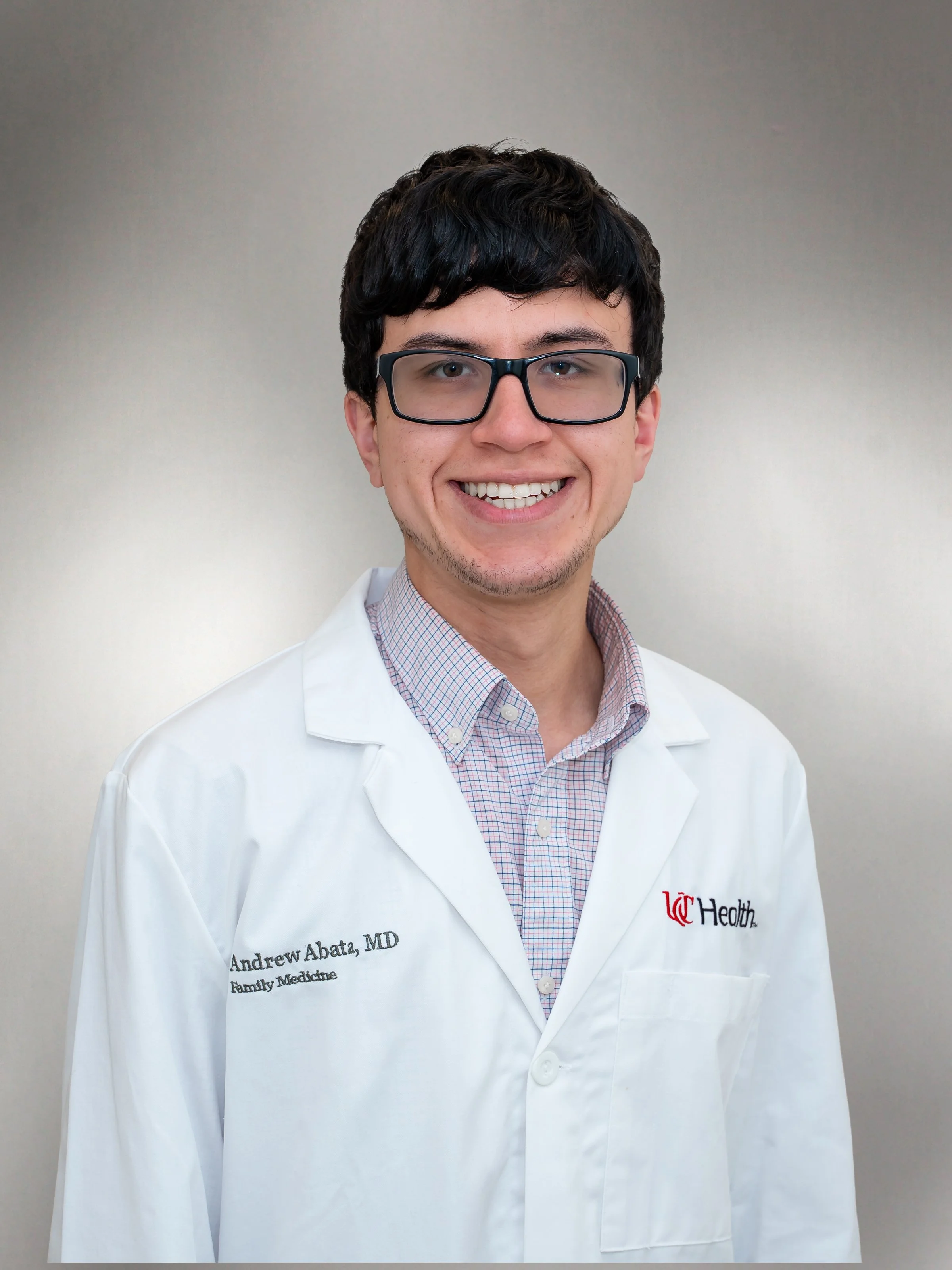 Dr. Andrew Abata wearing a white lab coat and smiling in a professional headshot.
