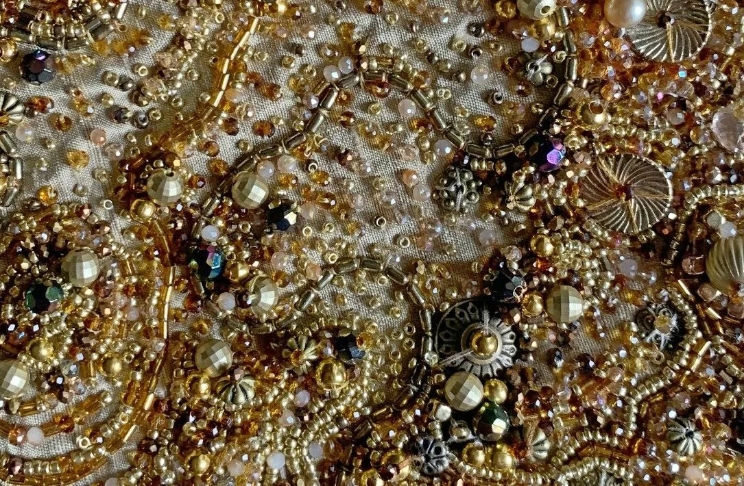 Various gold, silver, and crystal jewelry pieces scattered on a fabric surface, including beads, chains, and earrings.