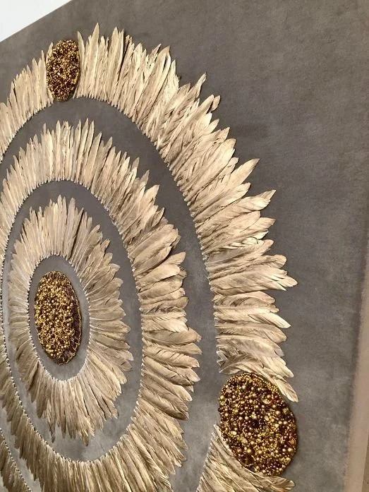 Decorative wall art with circular patterns made of white feathers and gold-speckled center accents.