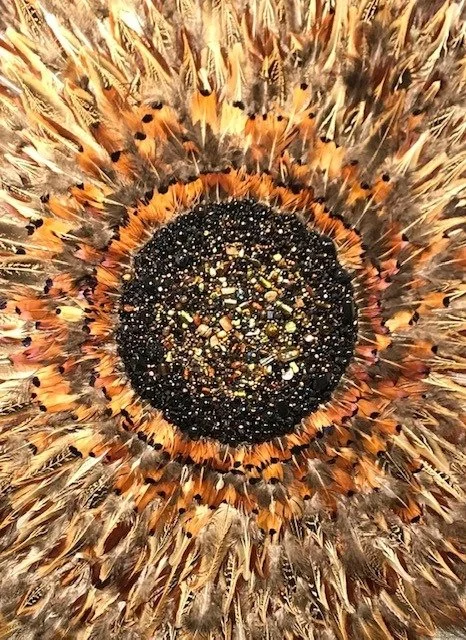 Close-up of a beaded artwork centre surrounded by duck and pheasant feathers