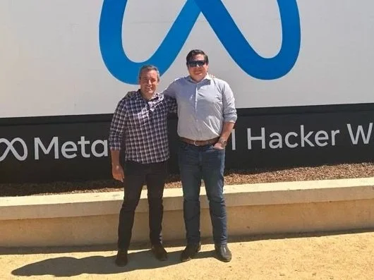 James and Chris stand in front of Meta sign