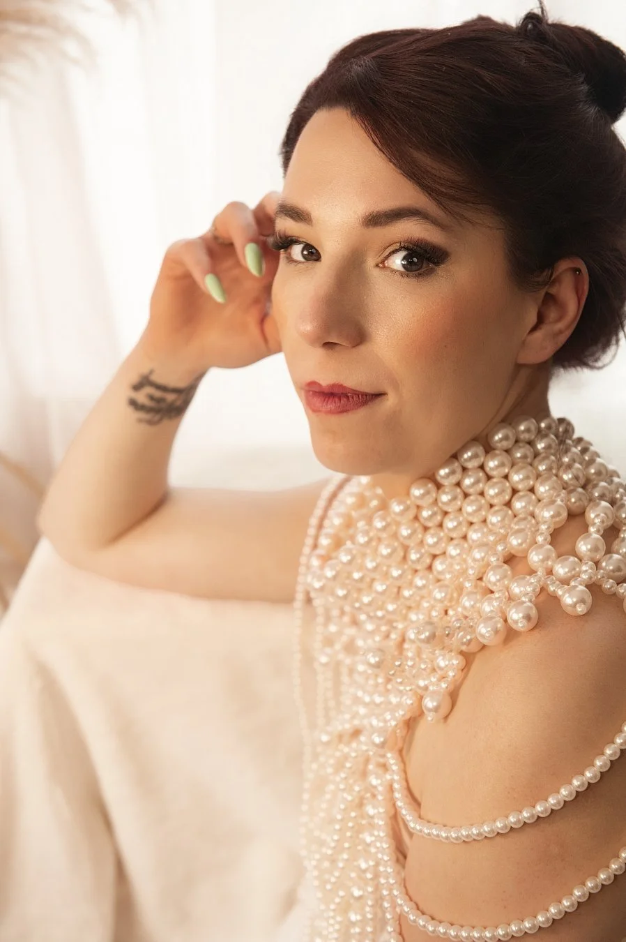 Beautiful woman with natural makeup, dark hair in statement pearl necklace, on the angle looking to the camera