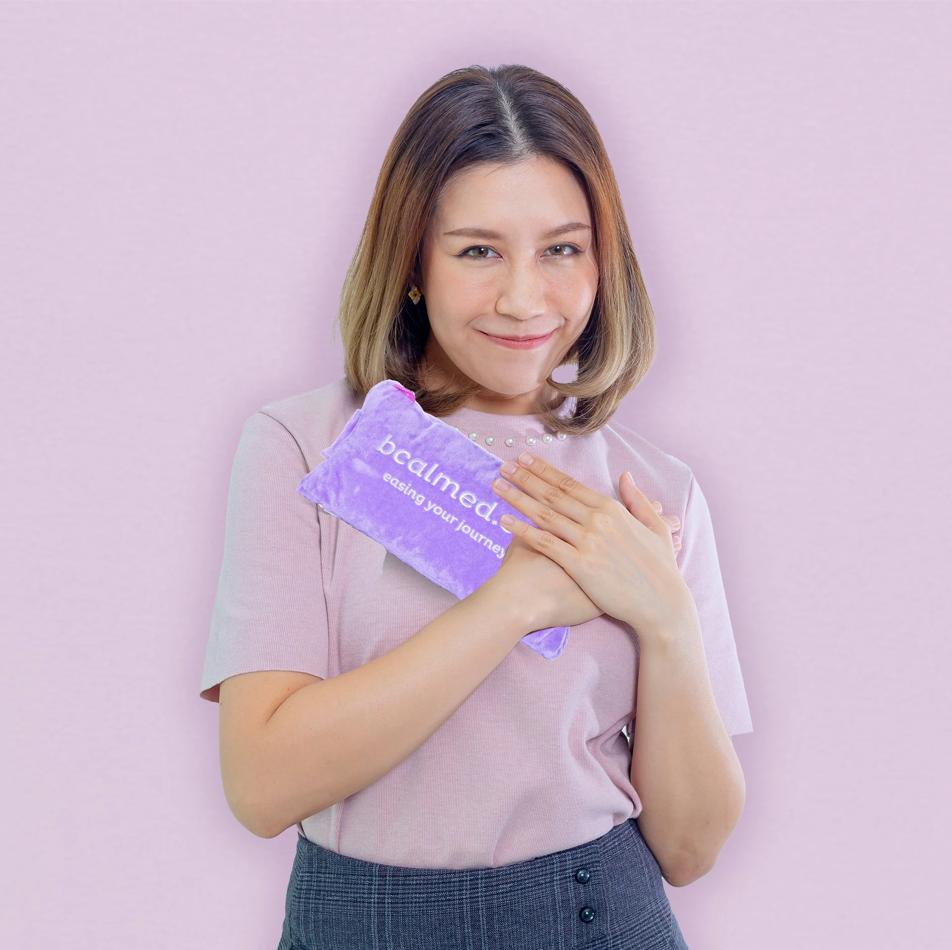 A smiling woman holding a bcalmed comfort cushion