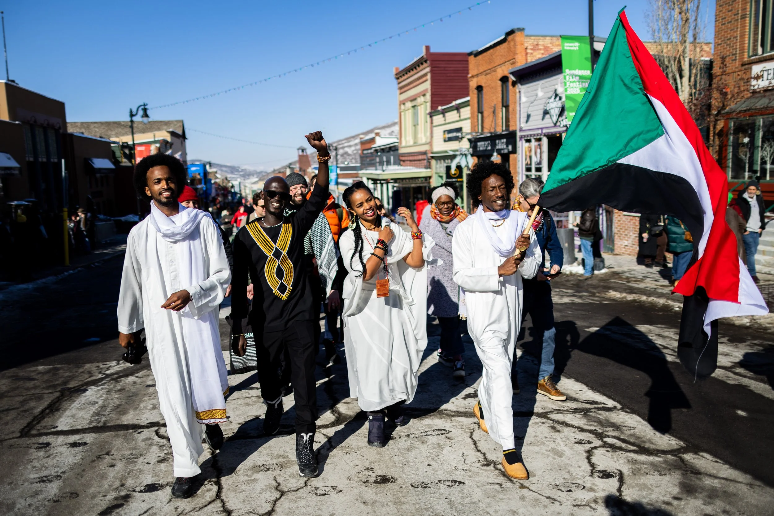  “Khartoum” Sudanese directors Timeea Mohamed Ahmed, Anas Saeed, Rawia Alhag, and Ibrahim Snoopy, from left, and the film team behind them walk on Main Street to the Egyptian Theatre with the Sudanese flag for the world premiere of their documentary 