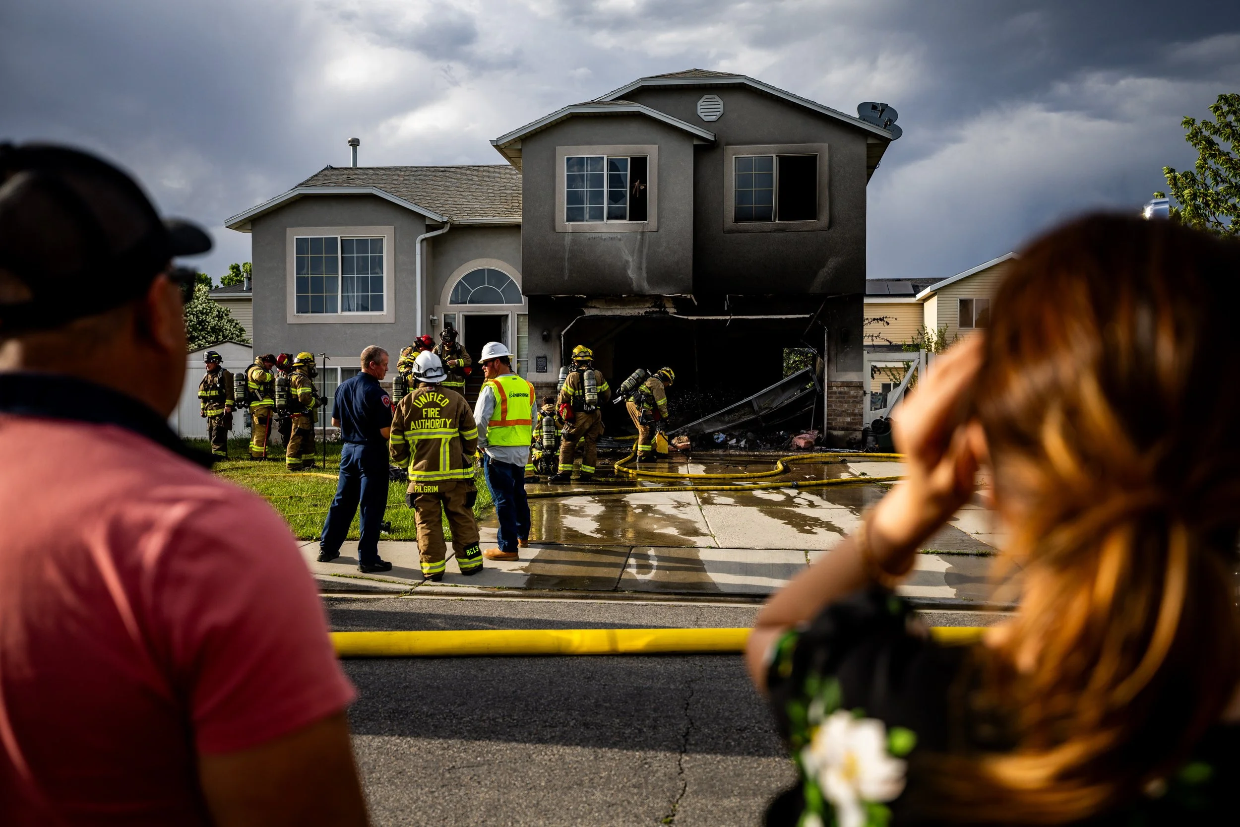  People watch as West Valley City firefighters work the scene at a garage fire at 3310 W Montrone Drive in West Valley City on Sunday, May 11, 2025.  